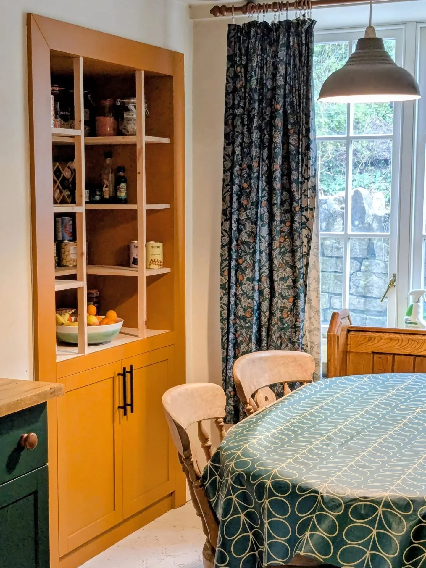 Tangerine dream bespoke larder cabinet for a family kitchen featuring open shelving above for everyday staples and a fruit bowl that's easy for the kids to reach. Below there's space for the big boxes and even to hide the plumbing, and all finished i
