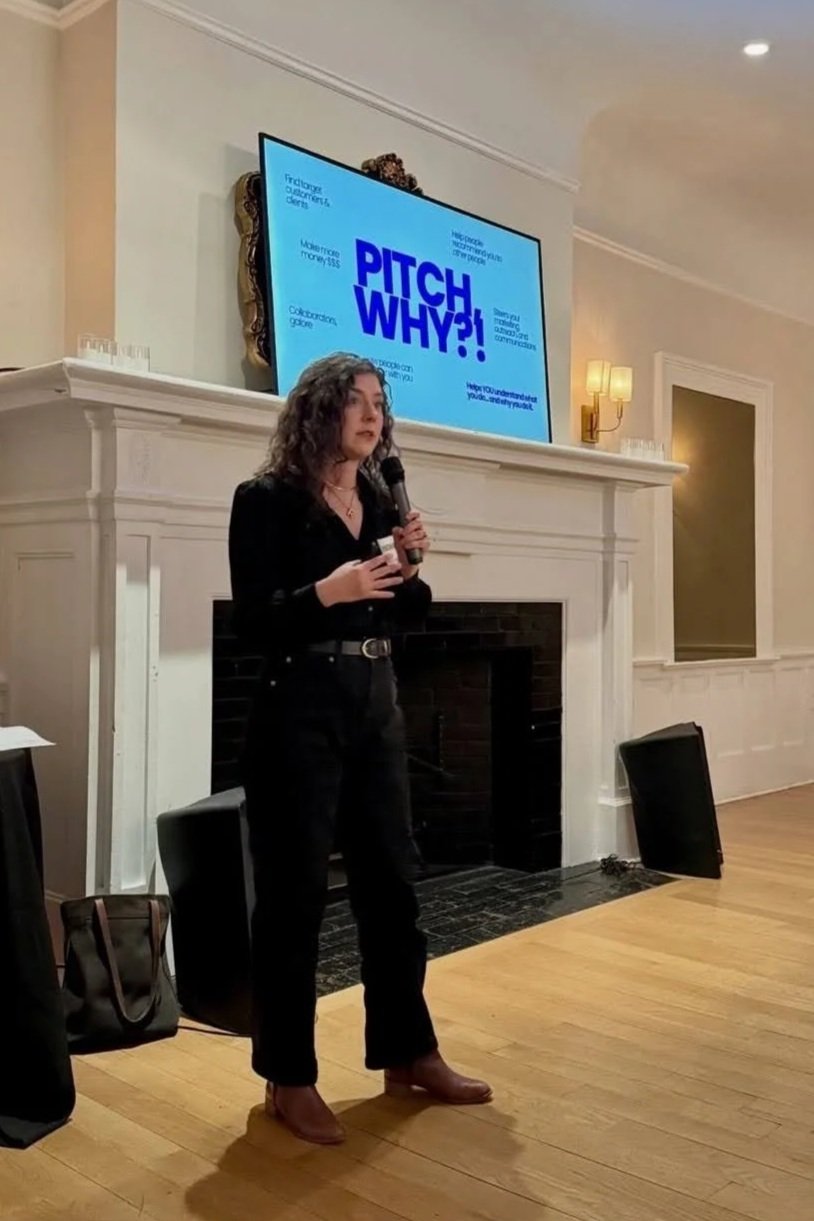 Image of Rikki Goldenberg speaking at an event holding a microphone