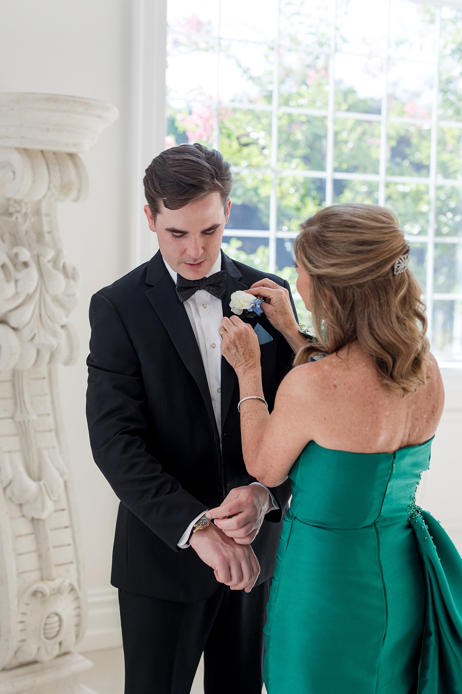  mother of groom helping her son with boutonniere  