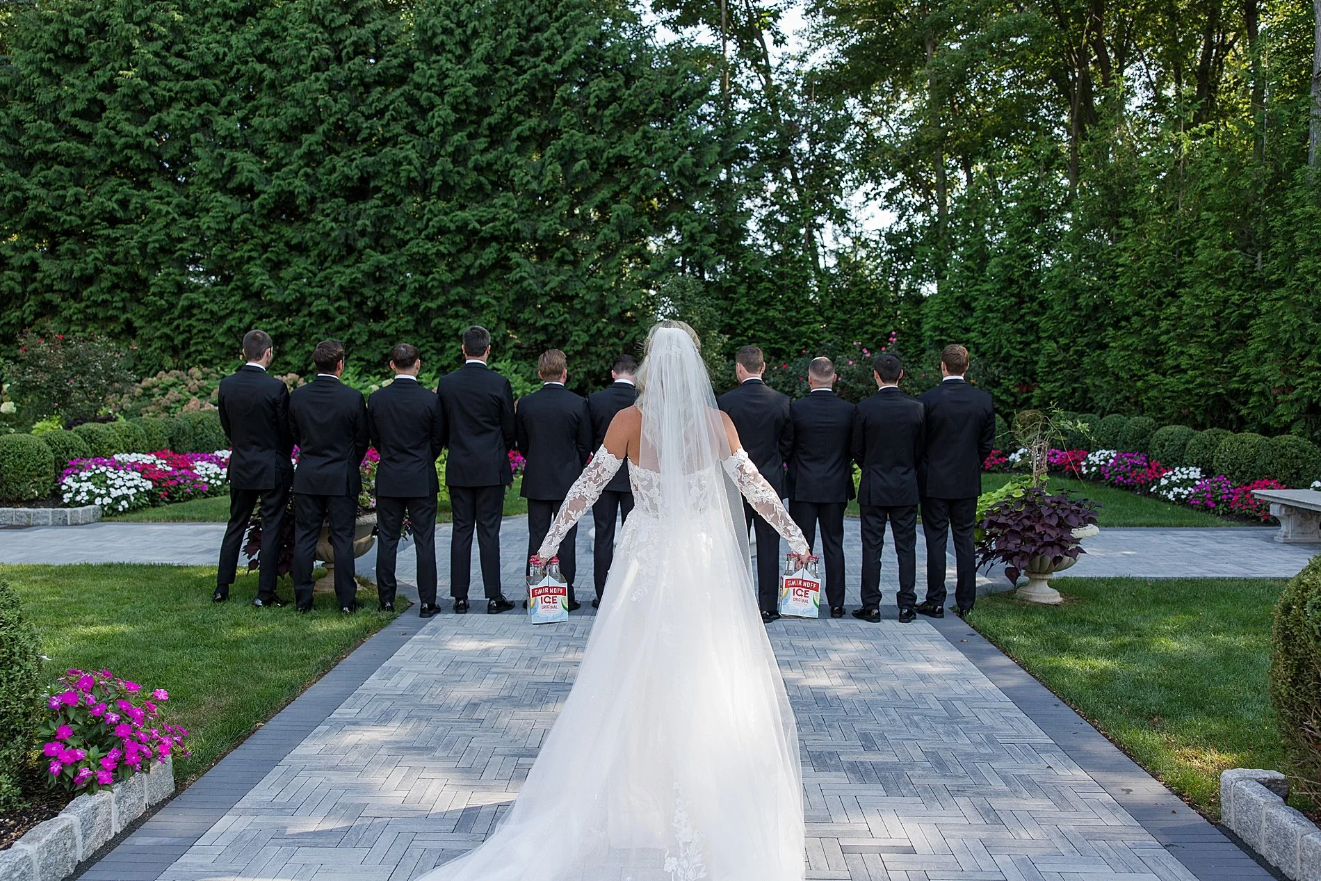 bride approaches groomsmen for first look with drinks  