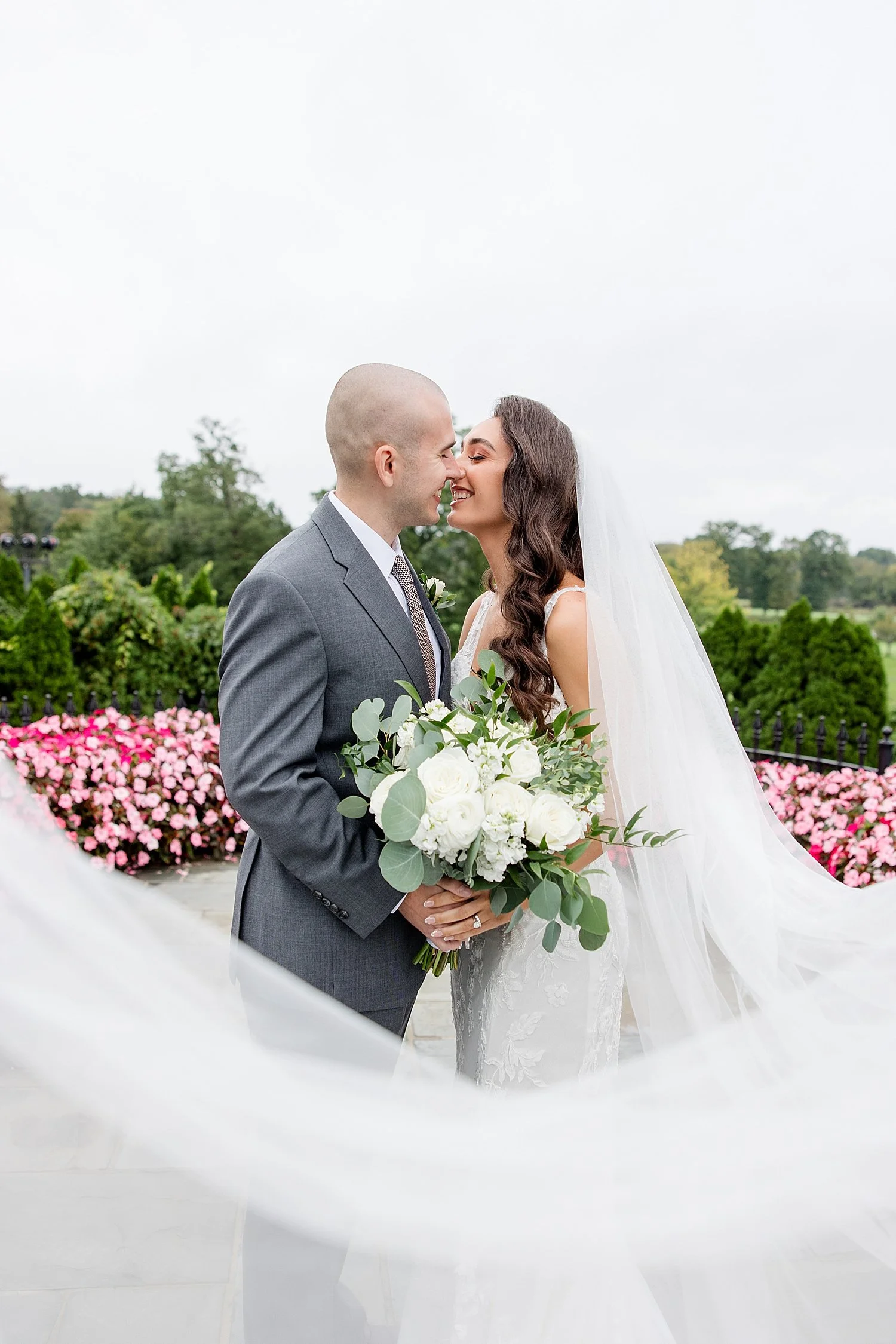  Bride and groom kiss with wedding veil surrounding them 