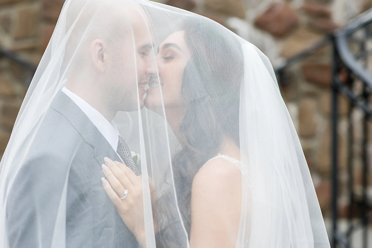  bride and groom kiss under bride’s veil 