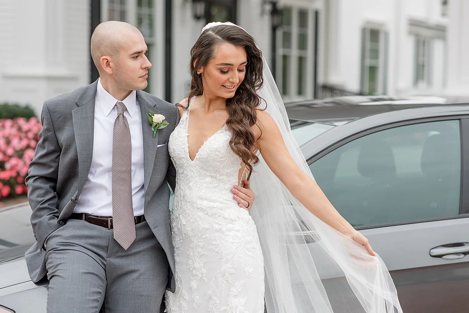  bride and groom stand by groom’s car 