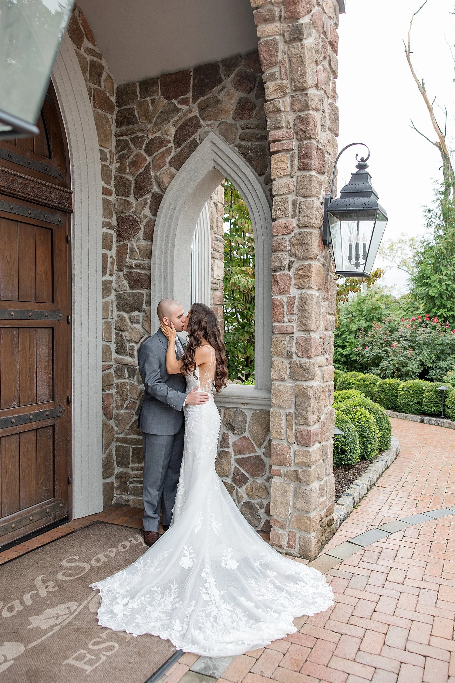  newlyweds kiss as they lean up agains stone siding of building  
