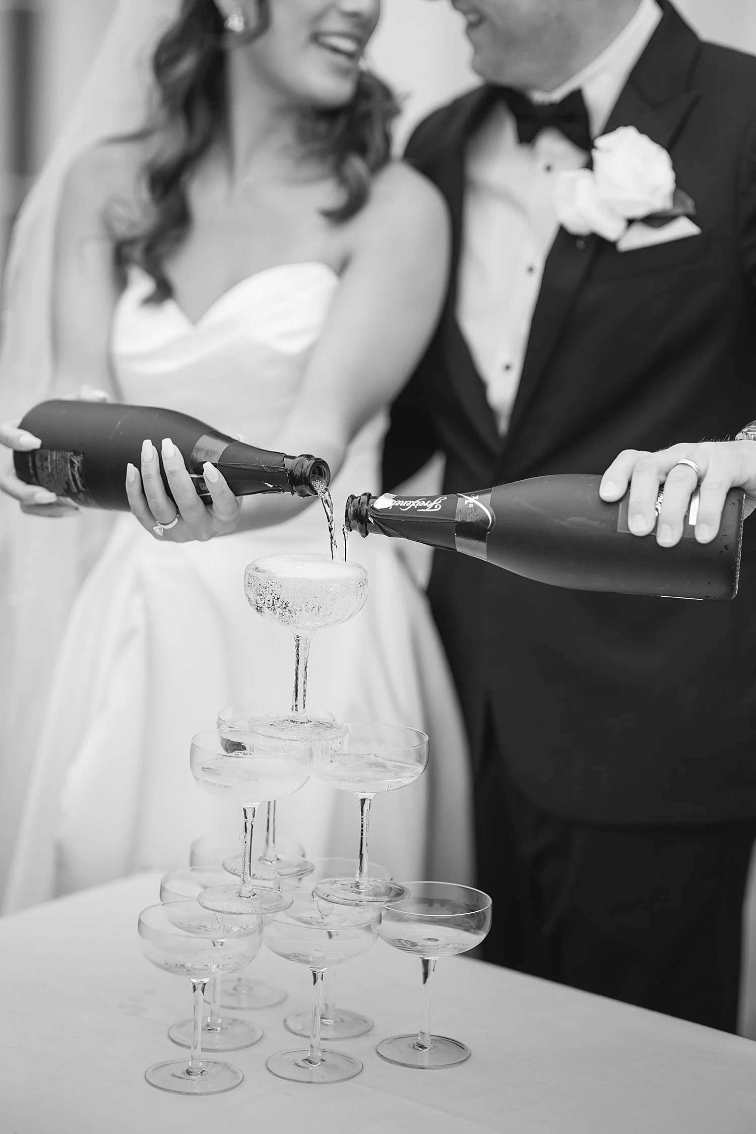  bride and groom pour champagne on tower of glasses 