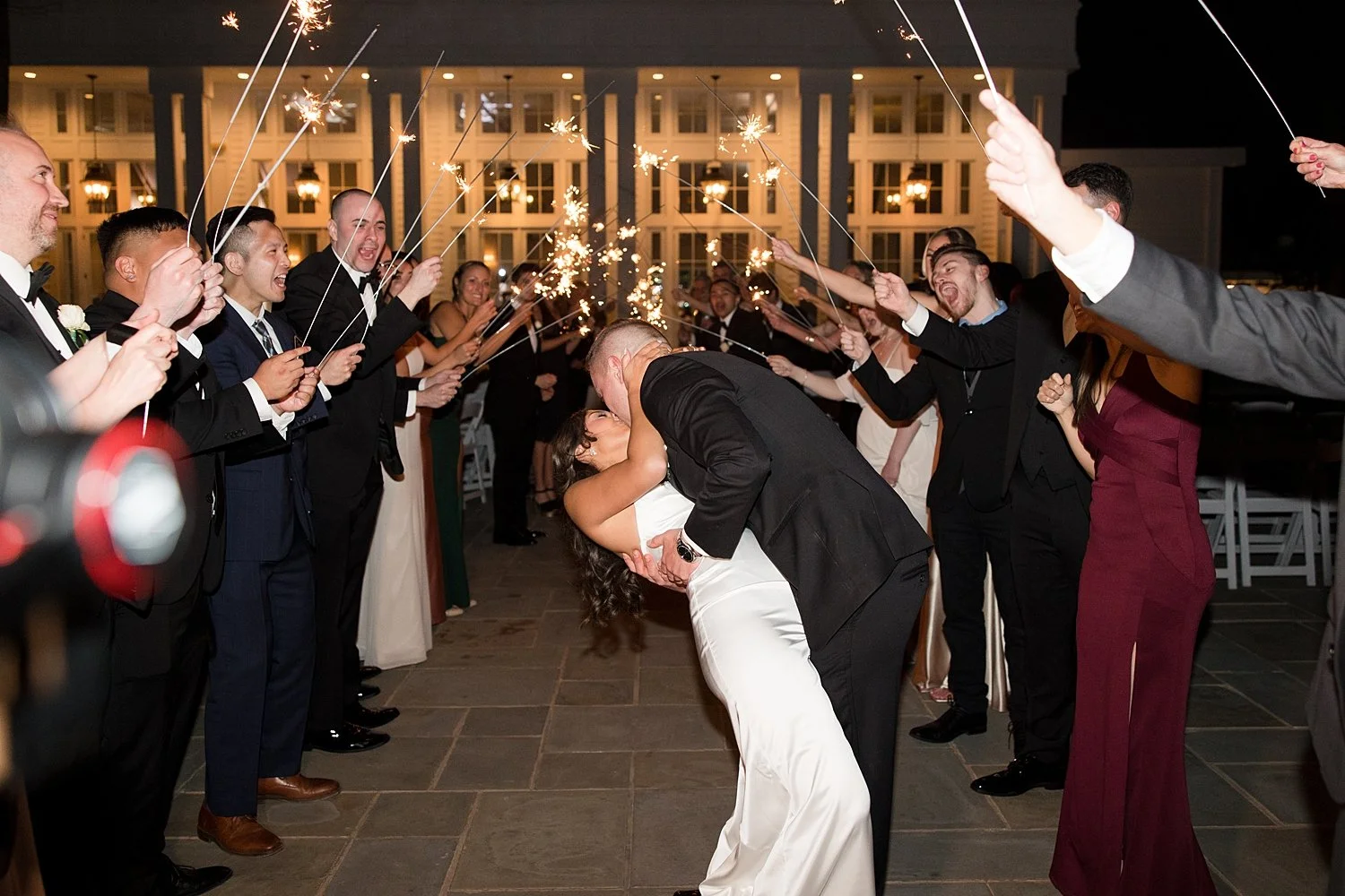  Newlyweds kiss as they exit wedding with guests holding sparklers  
