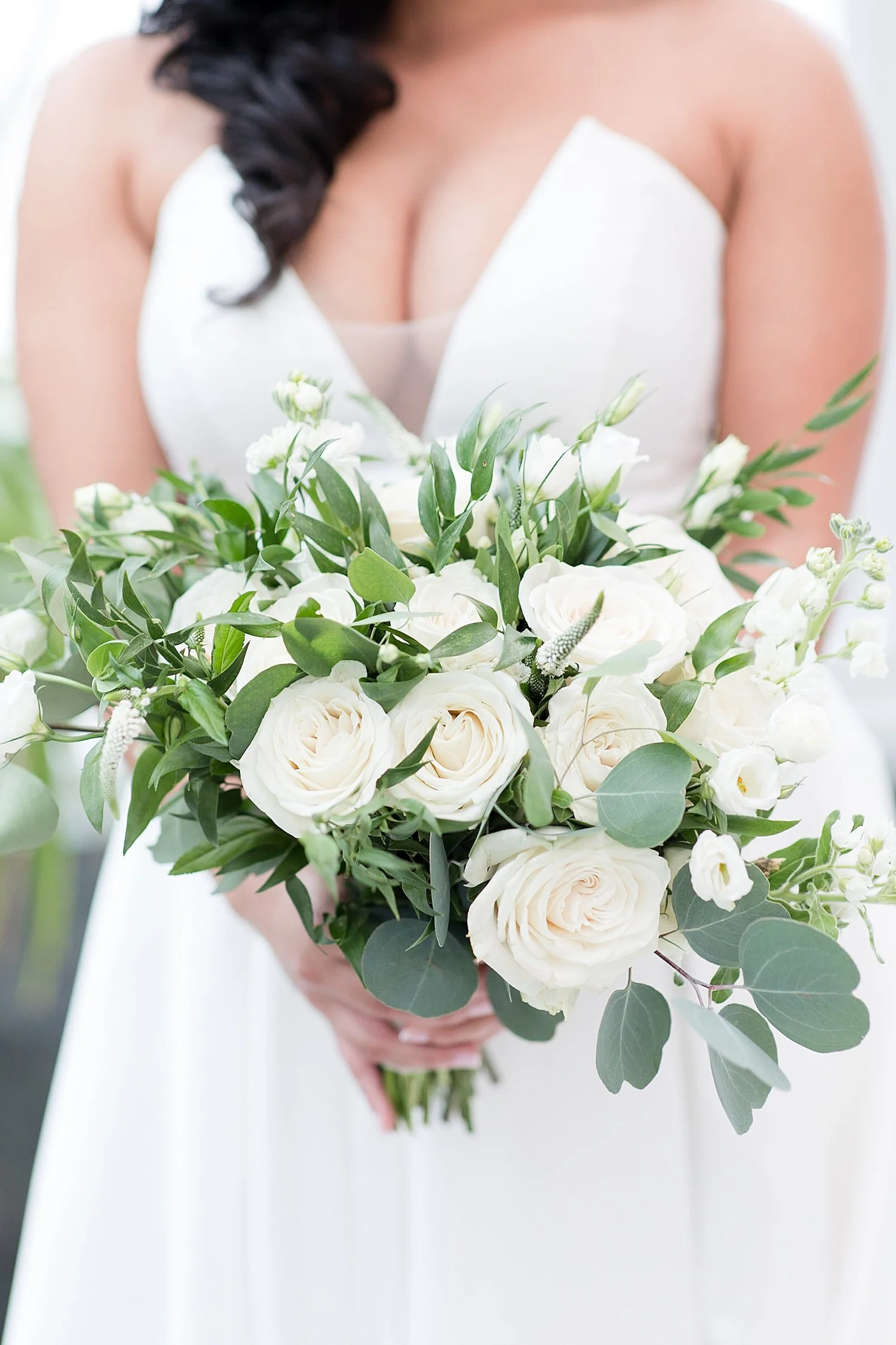  bride holding white rose bouquet with greenery  