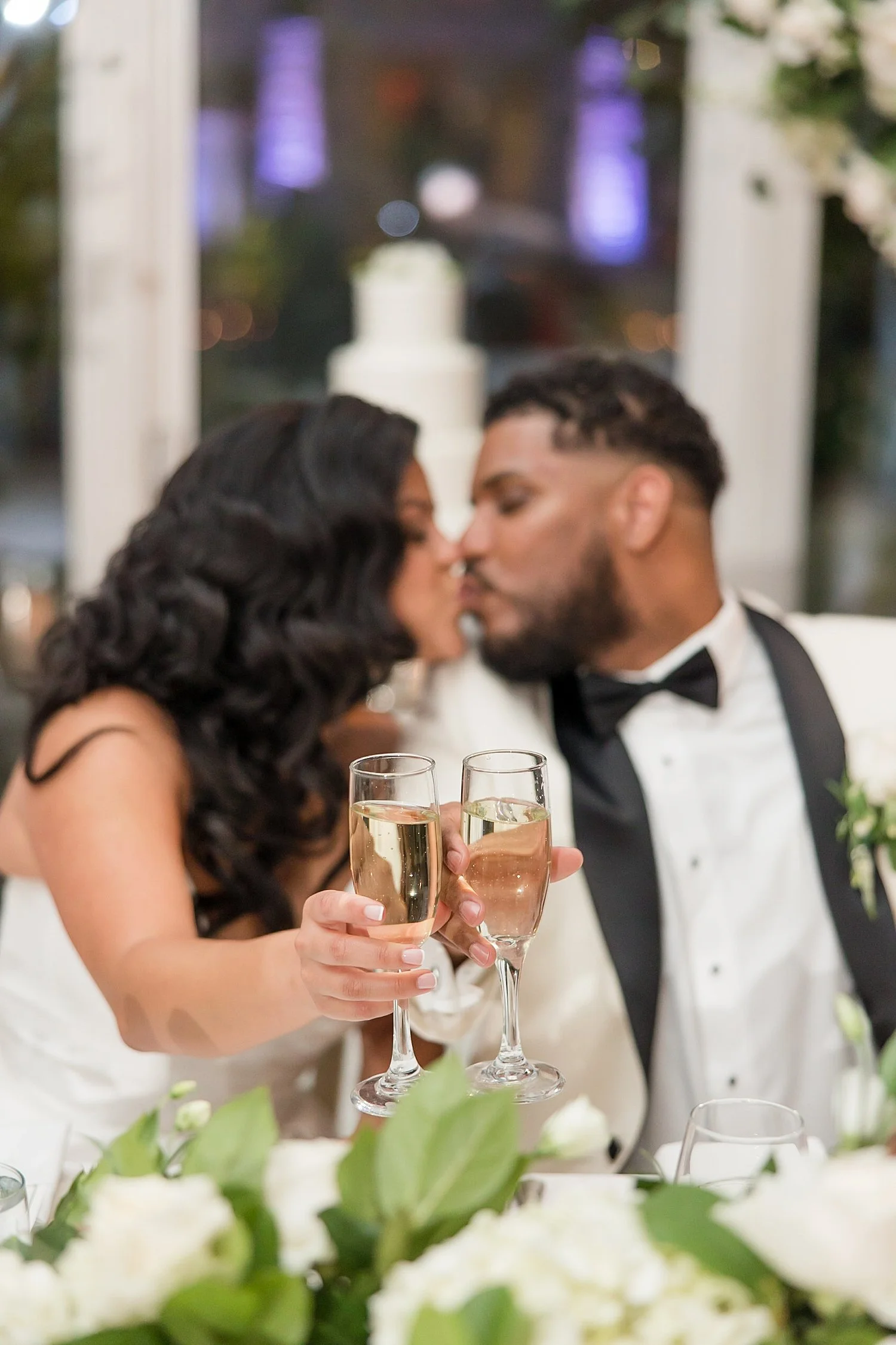  bride and groom kiss with glass of champagne  