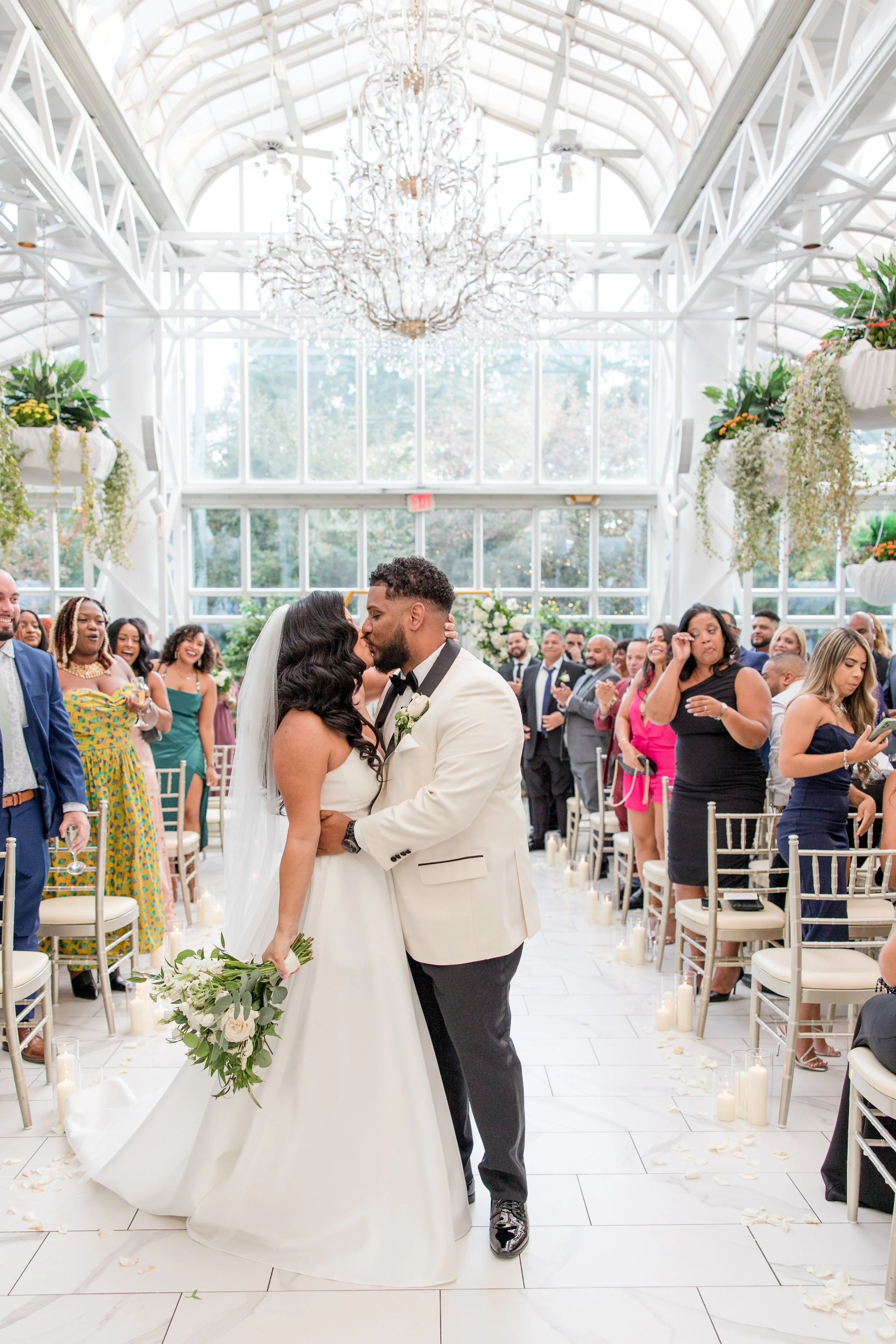 Bride and groom kiss in aisle after greenhouse wedding ceremony at The Park Savoy Estate in Florham Park, NJ. Photo by Jessica Anne Photography