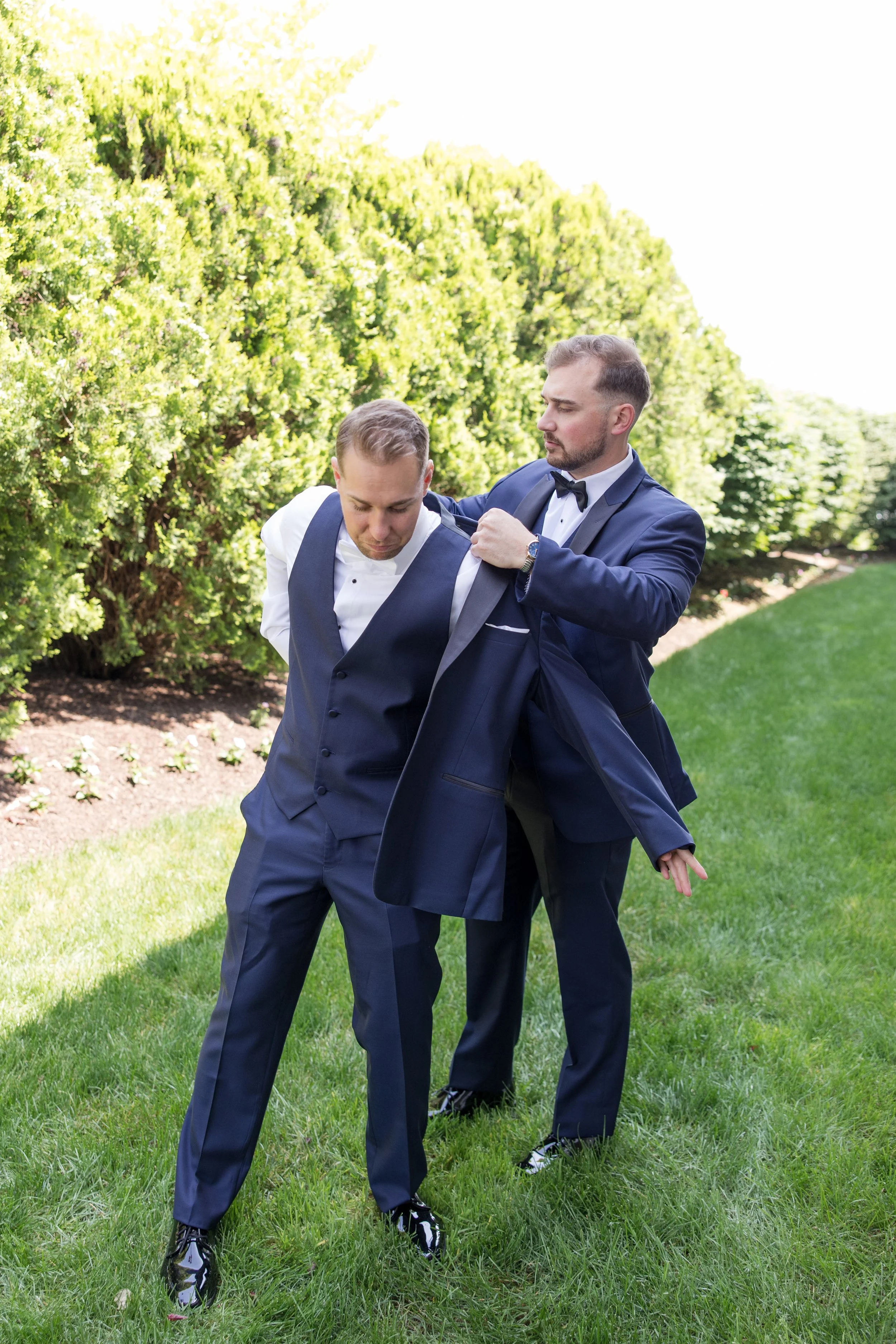 Best man helping groom put on jacket. Photo by Jessica Anne Photography at Crystal Point Yacht Club in Point Pleasant, NJ