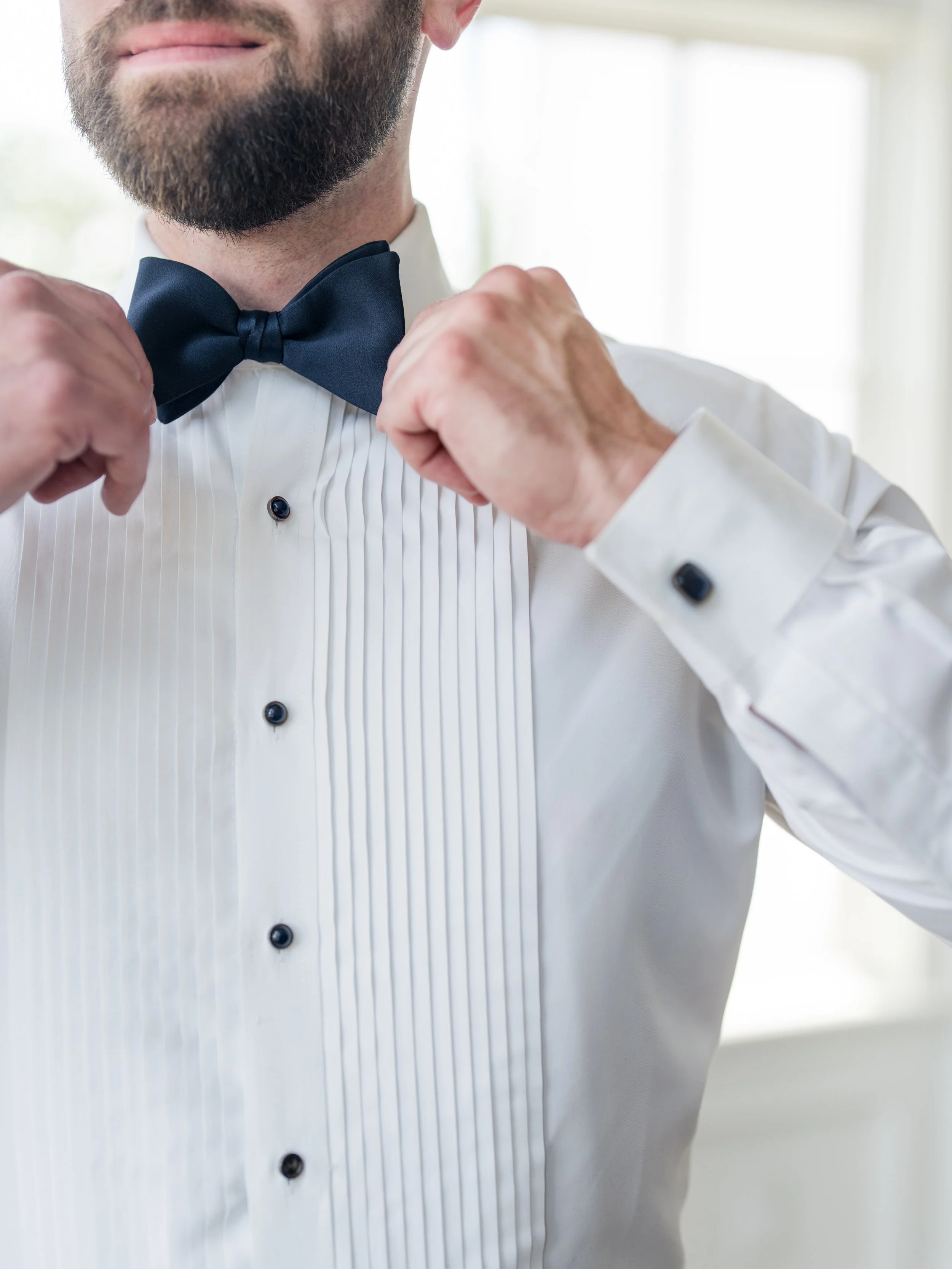 Groom tying bow tie. Closeup solo shot getting ready by New Jersey wedding photographer, Jessica Anne Photography