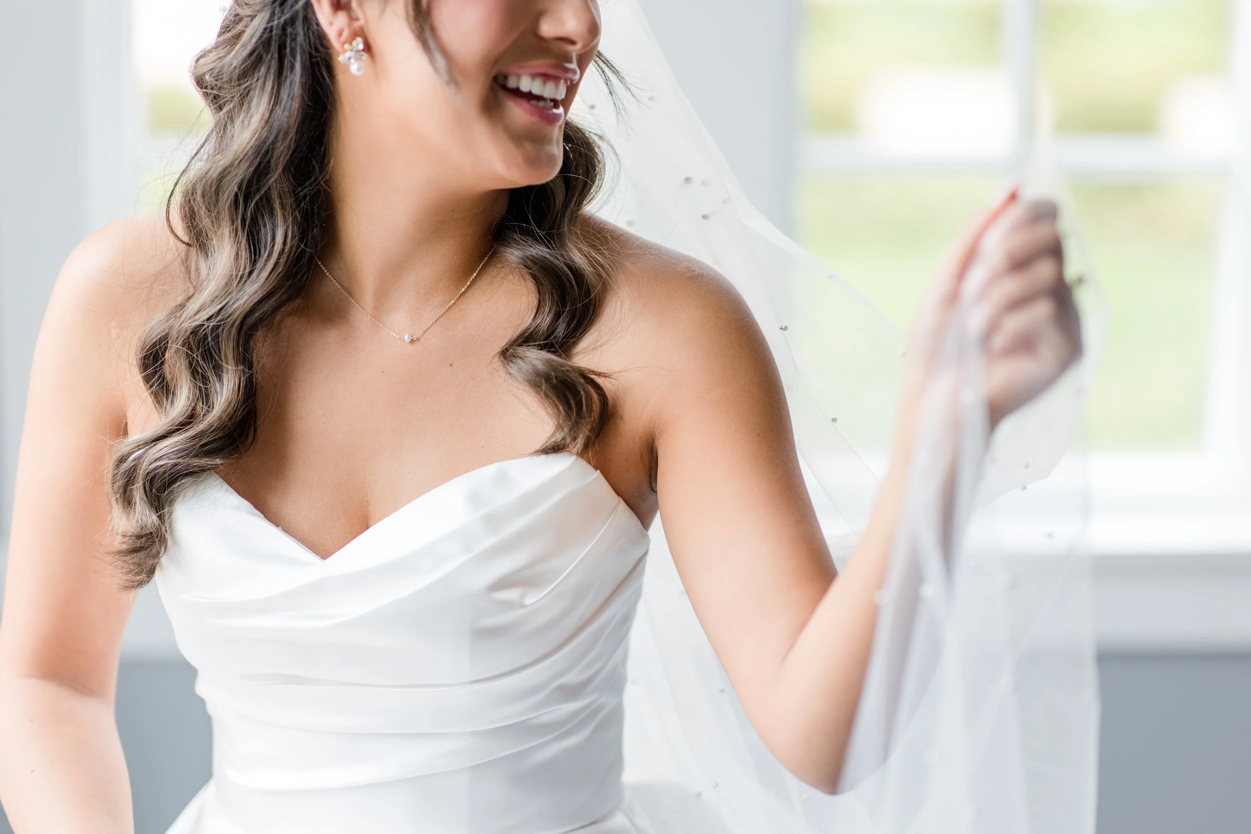 Closeup bride photo by Jessica Anne, NJ Wedding Photography. Bride holding veil  in strapless dress.
