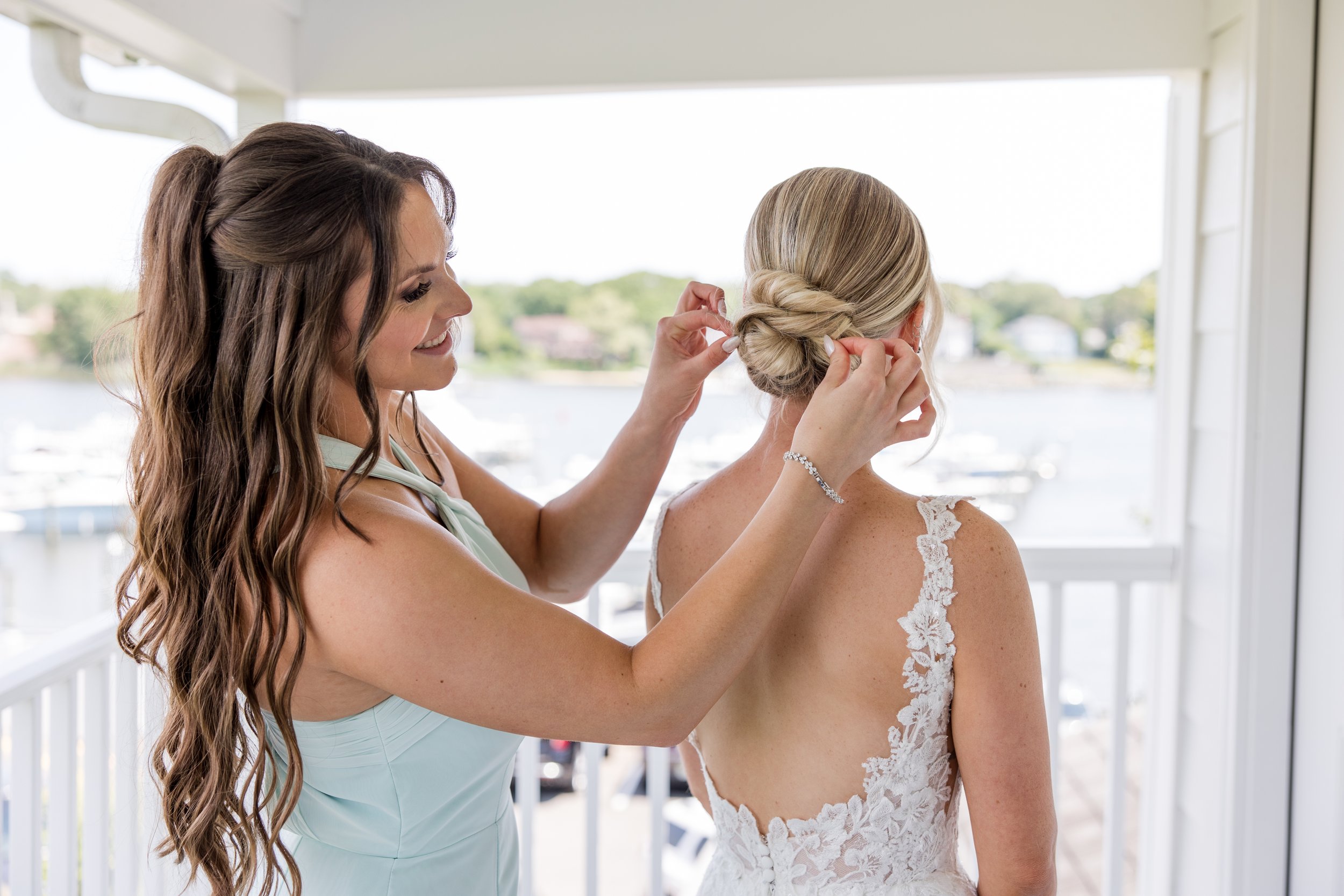 Maid of honor fixing brides hair. Getting ready photo by Jessica Anne Photography at Crystal Point Yacht Club in Point Pleasant, NJ