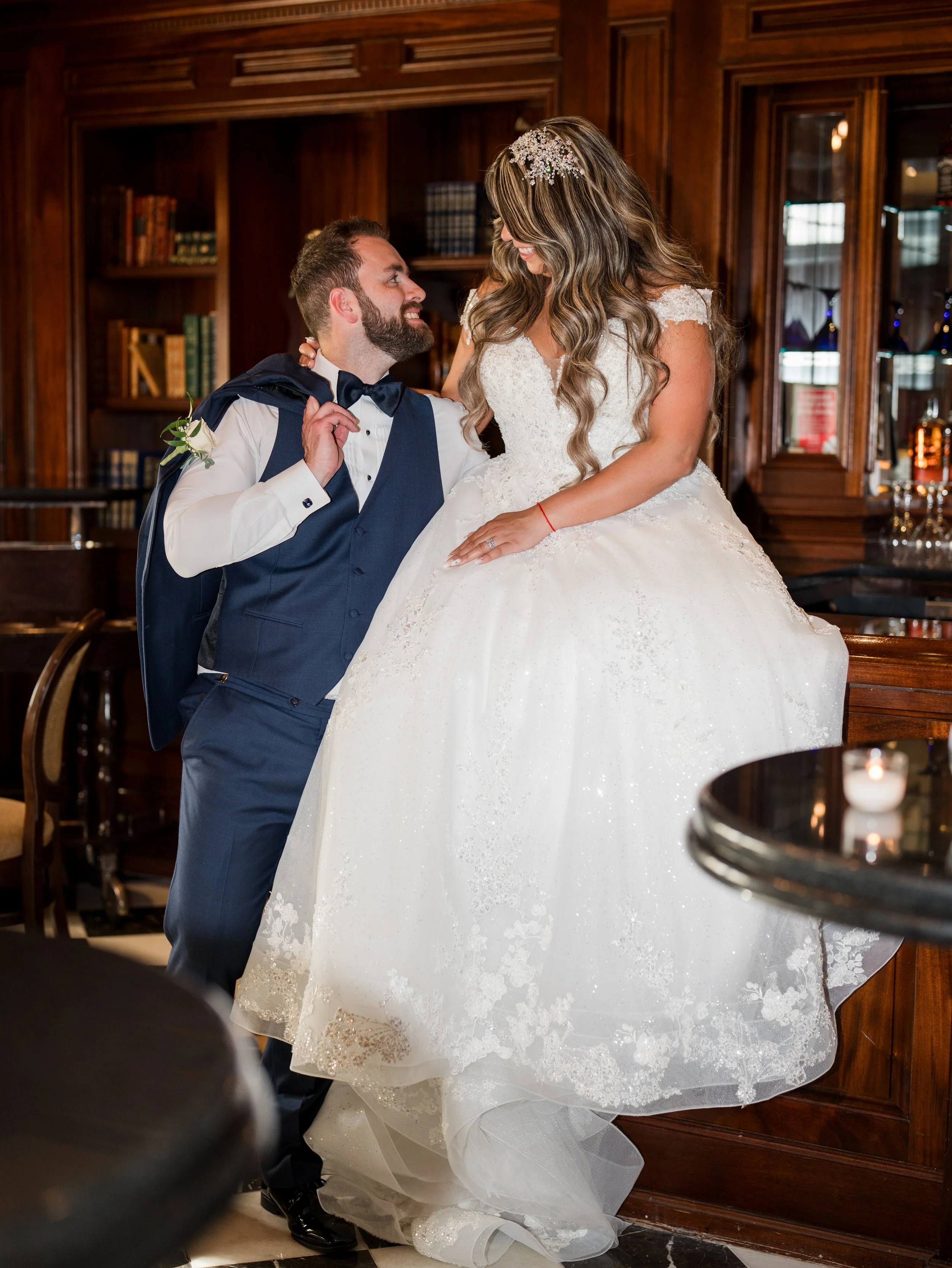 Broom looking lovingly at bride sitting on bar at The Park Savoy Estate in Florham Park, NJ by wedding photographer, Jessica Anne Photography