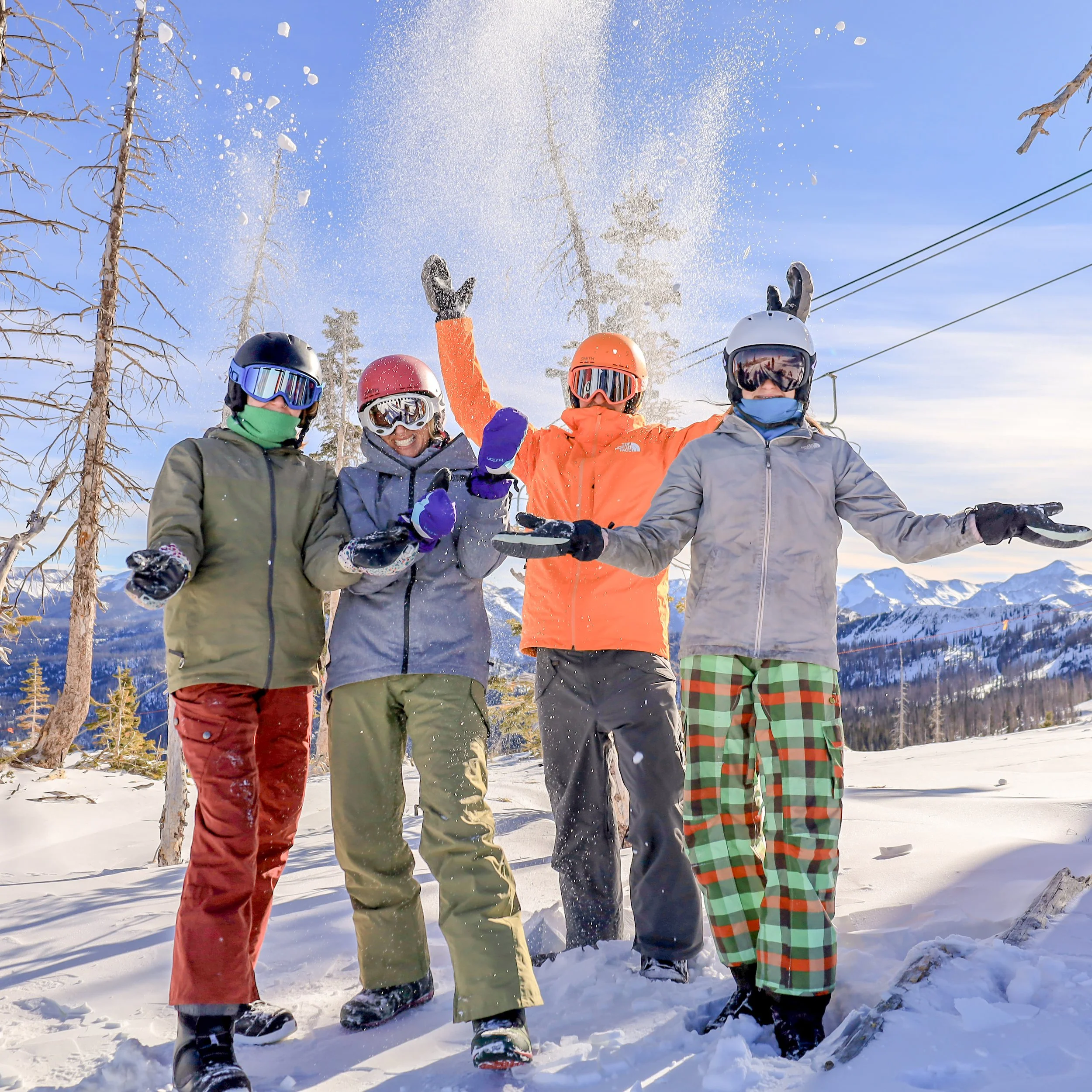 Two skiers in colorful race bibs celebrate at the finish of a snowy course.