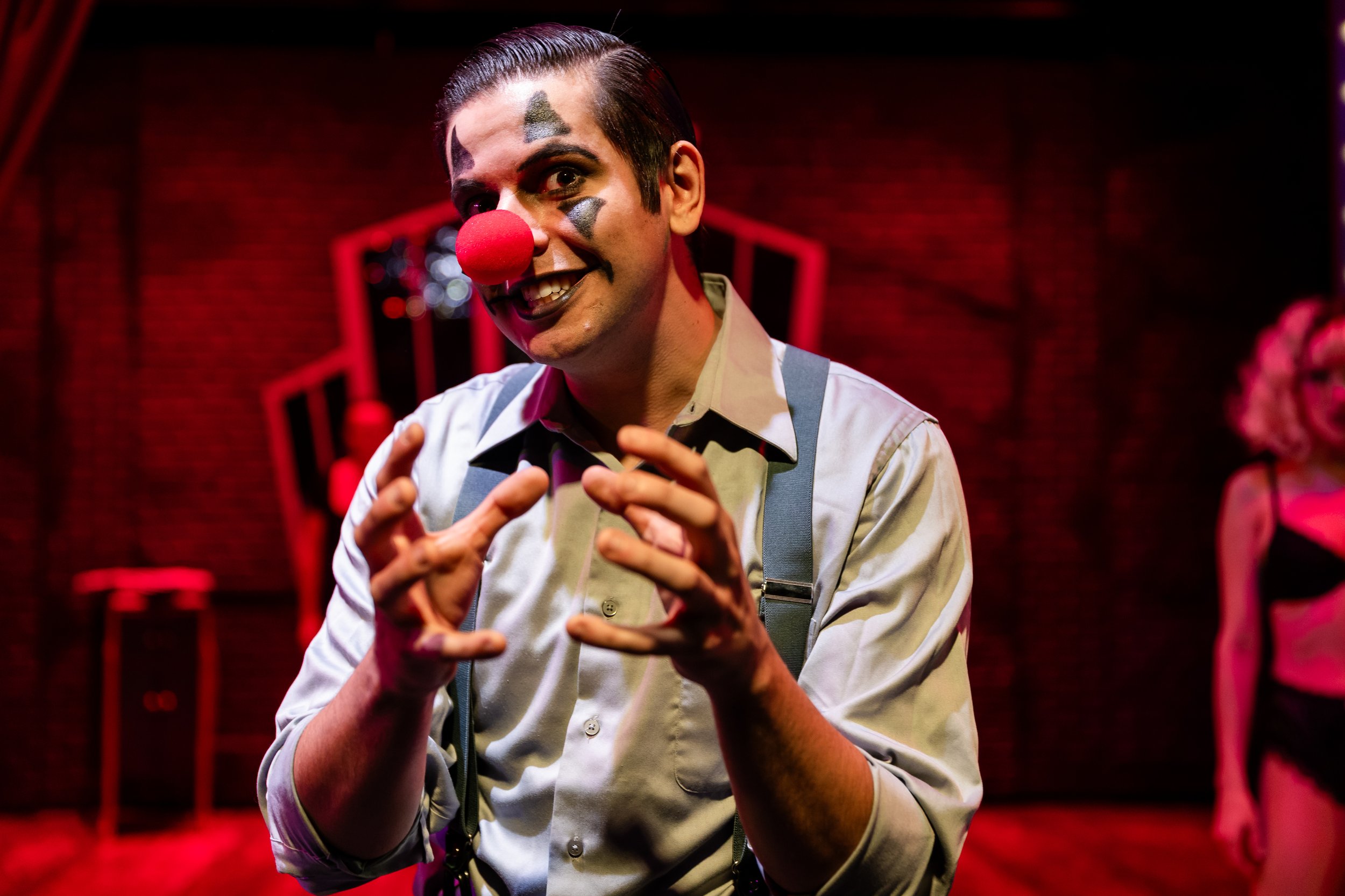 Singer performs into a microphone under red stage lighting.
