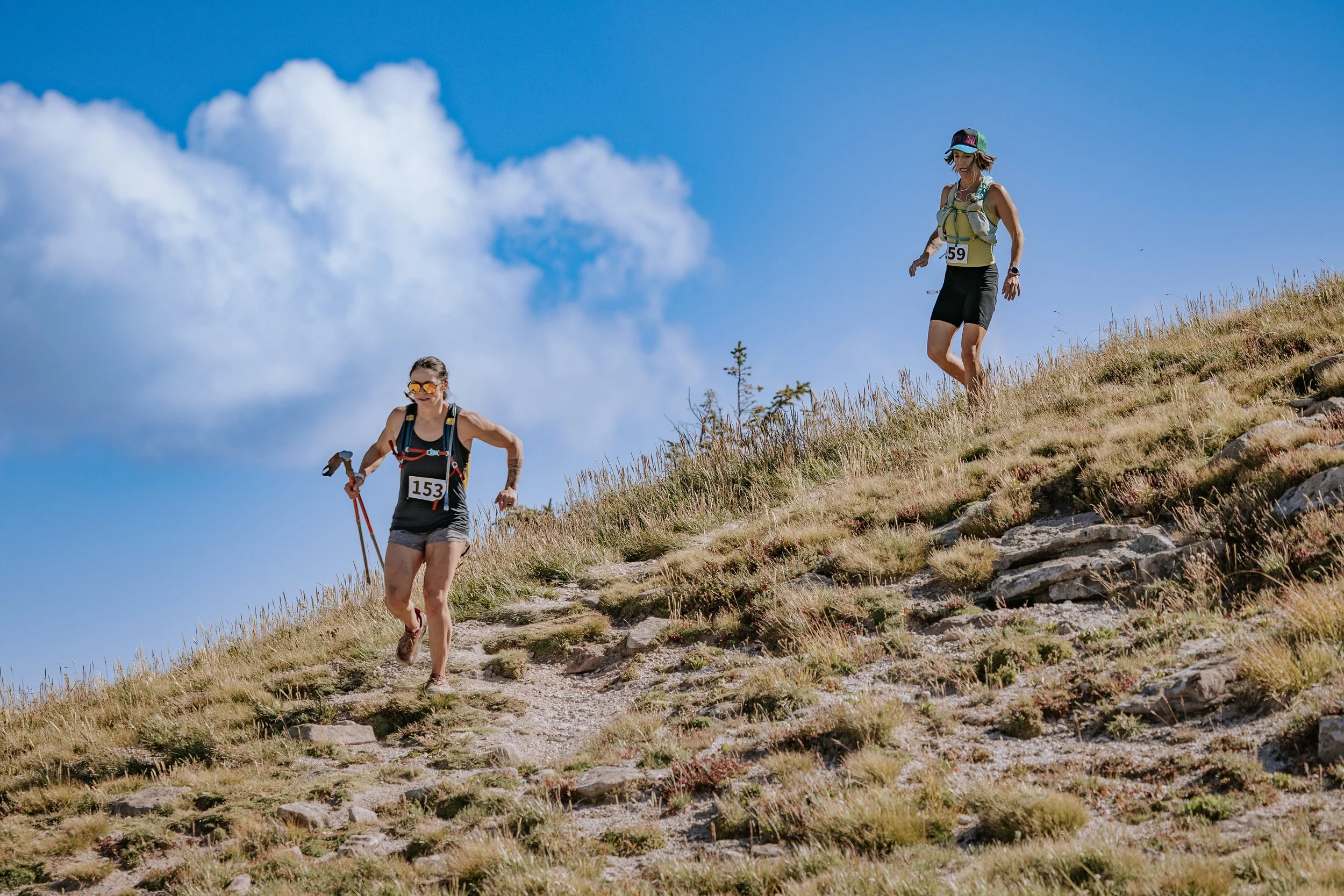 Trail runner climbs a rocky alpine slope during an outdoor race.