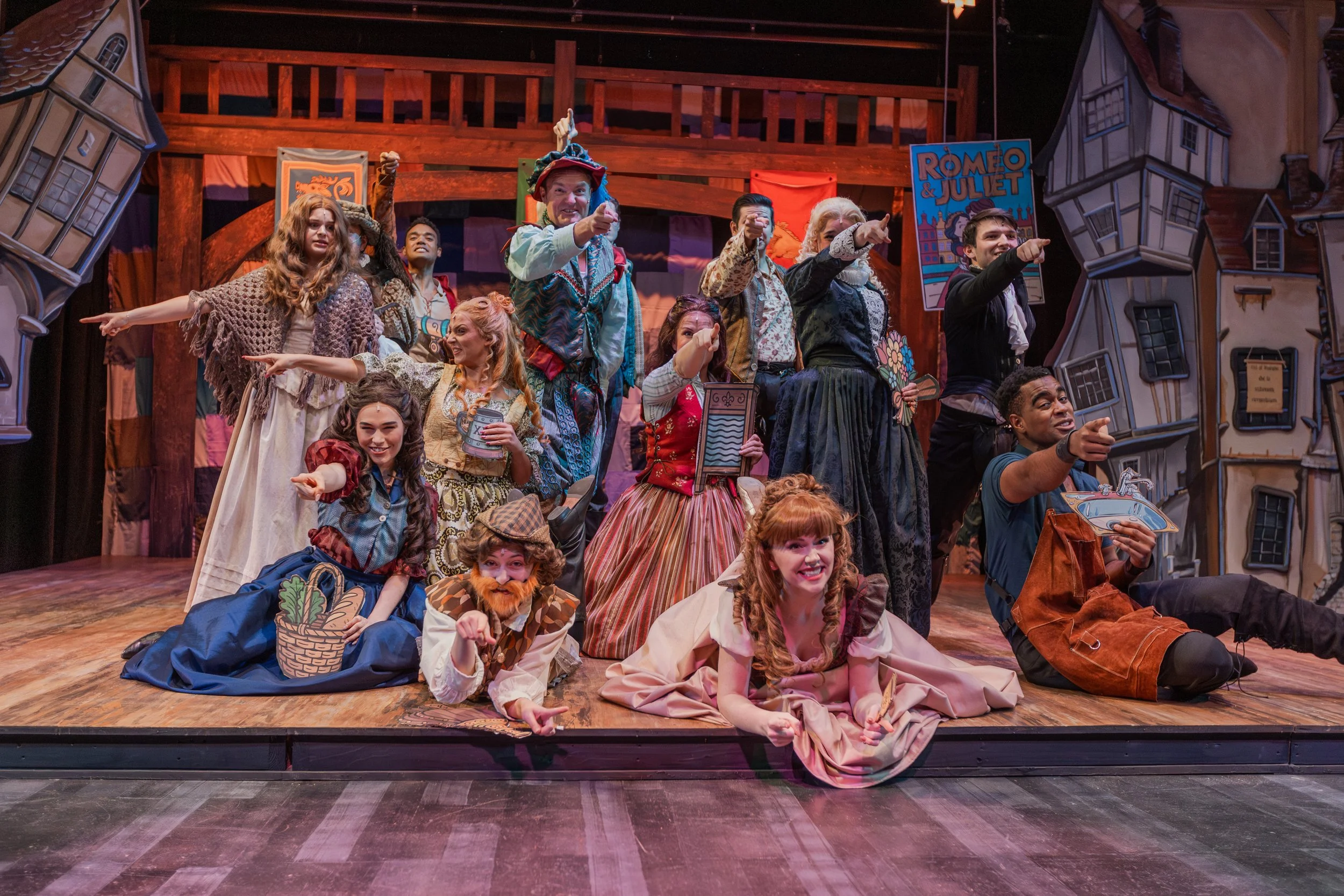 Theater cast gathers onstage in colorful costumes after a performance.