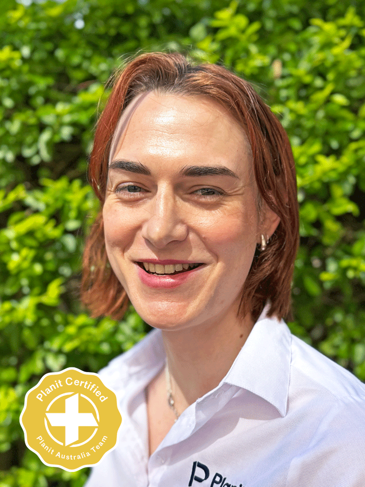 A smiling woman wearing a white button-up shirt with the word "Planit" on it, standing outdoors in front of green foliage. There is a gold and white "Planit Certified" badge in the bottom left corner.