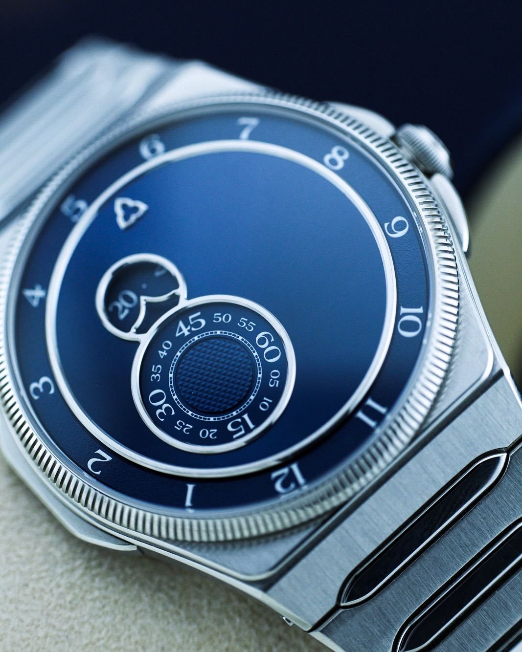 Time, set free.

No hands. Just three rotating worlds&mdash;hours drifting counter-clockwise at the periphery, minutes and seconds intertwined in a figure-eight ballet of grained texture and Clous de Paris guilloch&eacute;.

Turn the brutalist archit