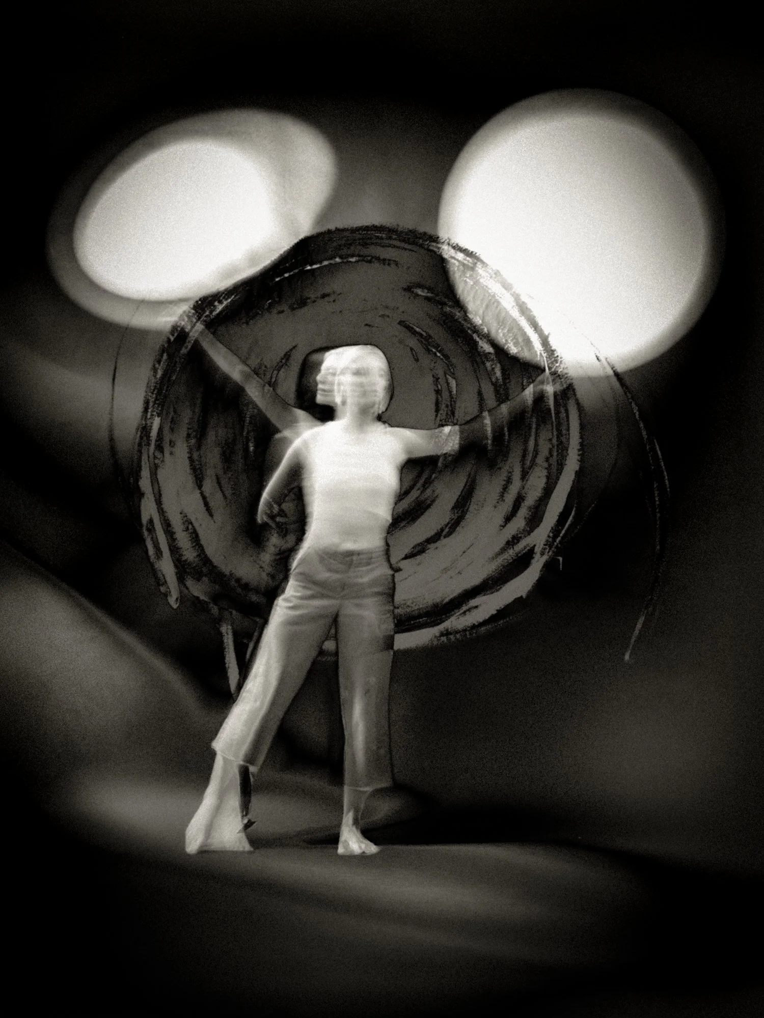 Surreal black-and-white fine art photograph of a standing figure framed by a swirling circular portal and twin glowing orbs, suggesting creation, cosmology, and transformation.