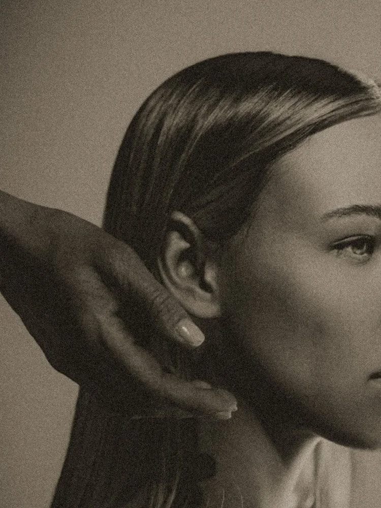 High-grain artistic photography close-up featuring a face in profile and an intimate hand gesture.