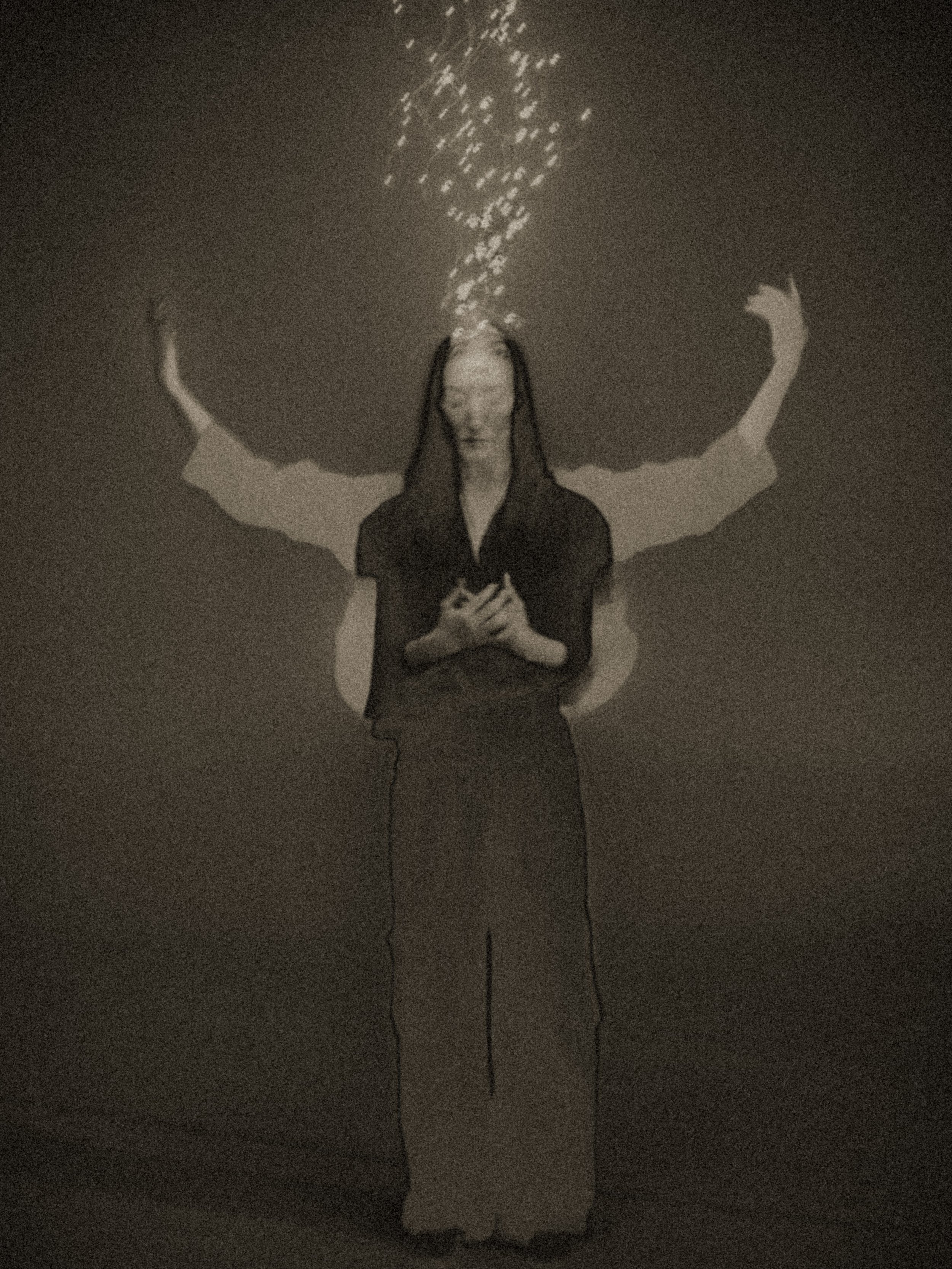 Surreal black-and-white portrait with layered, outstretched arms and a stream of bright particles rising above the head, suggesting ritual, ascension, and “light upon light” in a minimalist void.