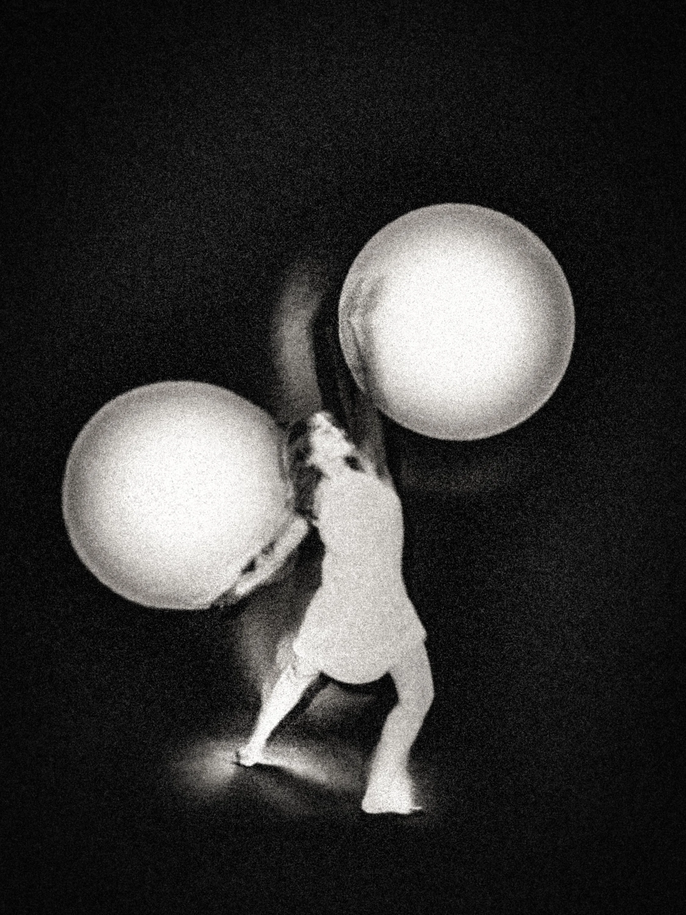 High-grain black-and-white fine art photograph of a nude figure balancing two glowing spheres against a deep black background, evoking gravity, burden, and cosmic symbolism.