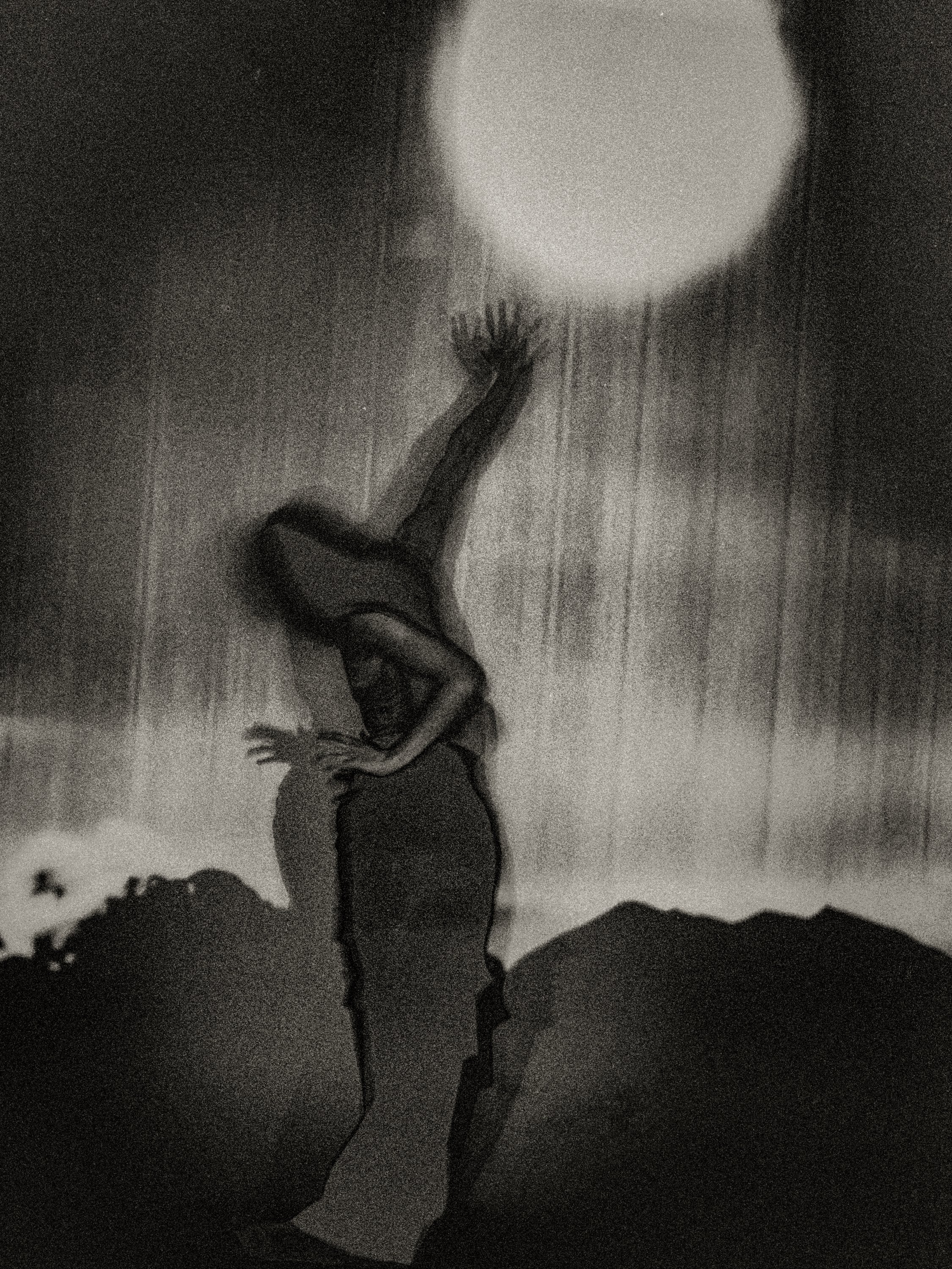 Surreal fine art photography of a silhouette figure reaching up towards a bright moon with heavy grain and shadow play.