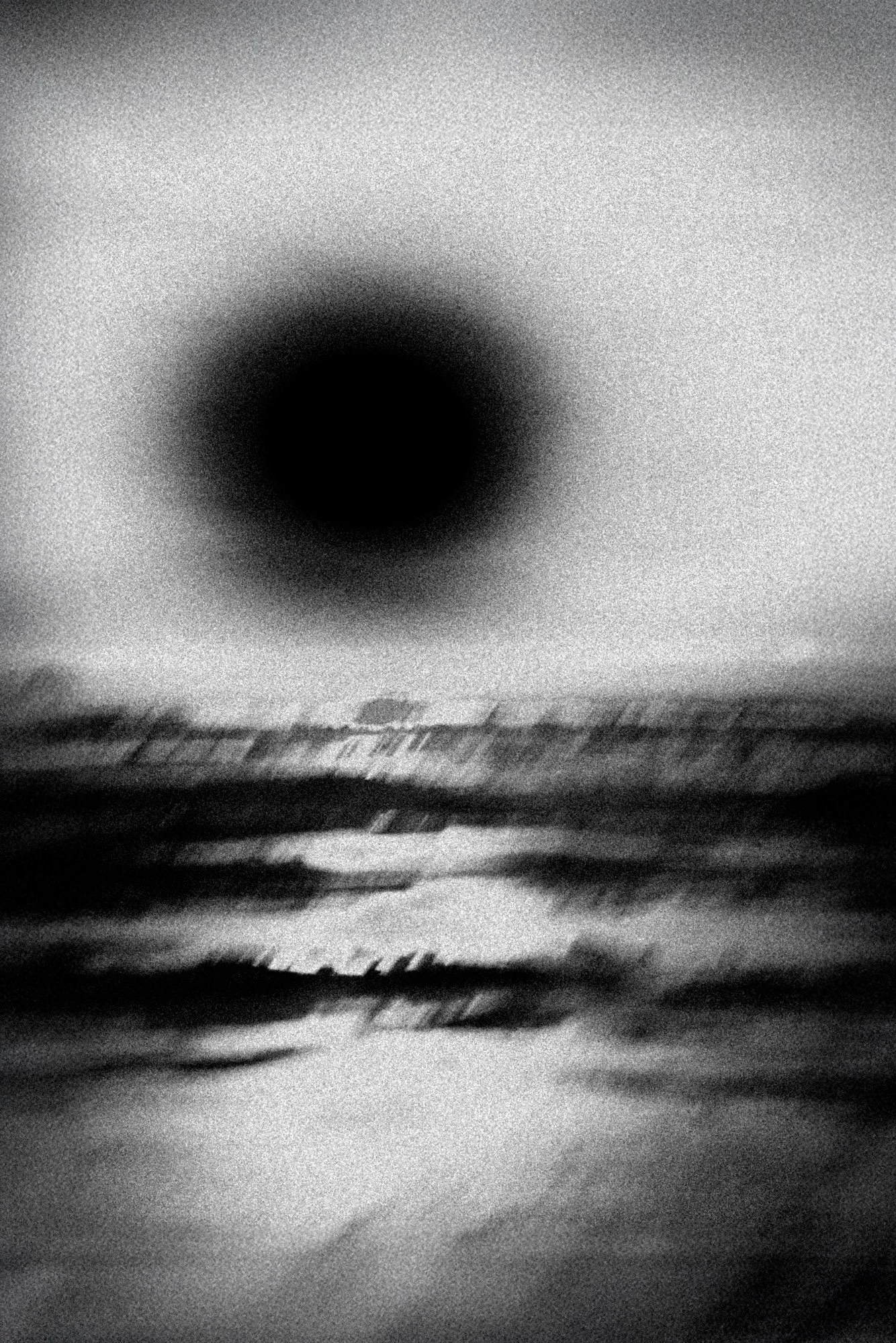 Abstract monochrome seascape with a dark eclipsed disc hovering above a blurred horizon—minimalist, contemporary art photography that suggests cosmic silence, mystery, and the edge of night.