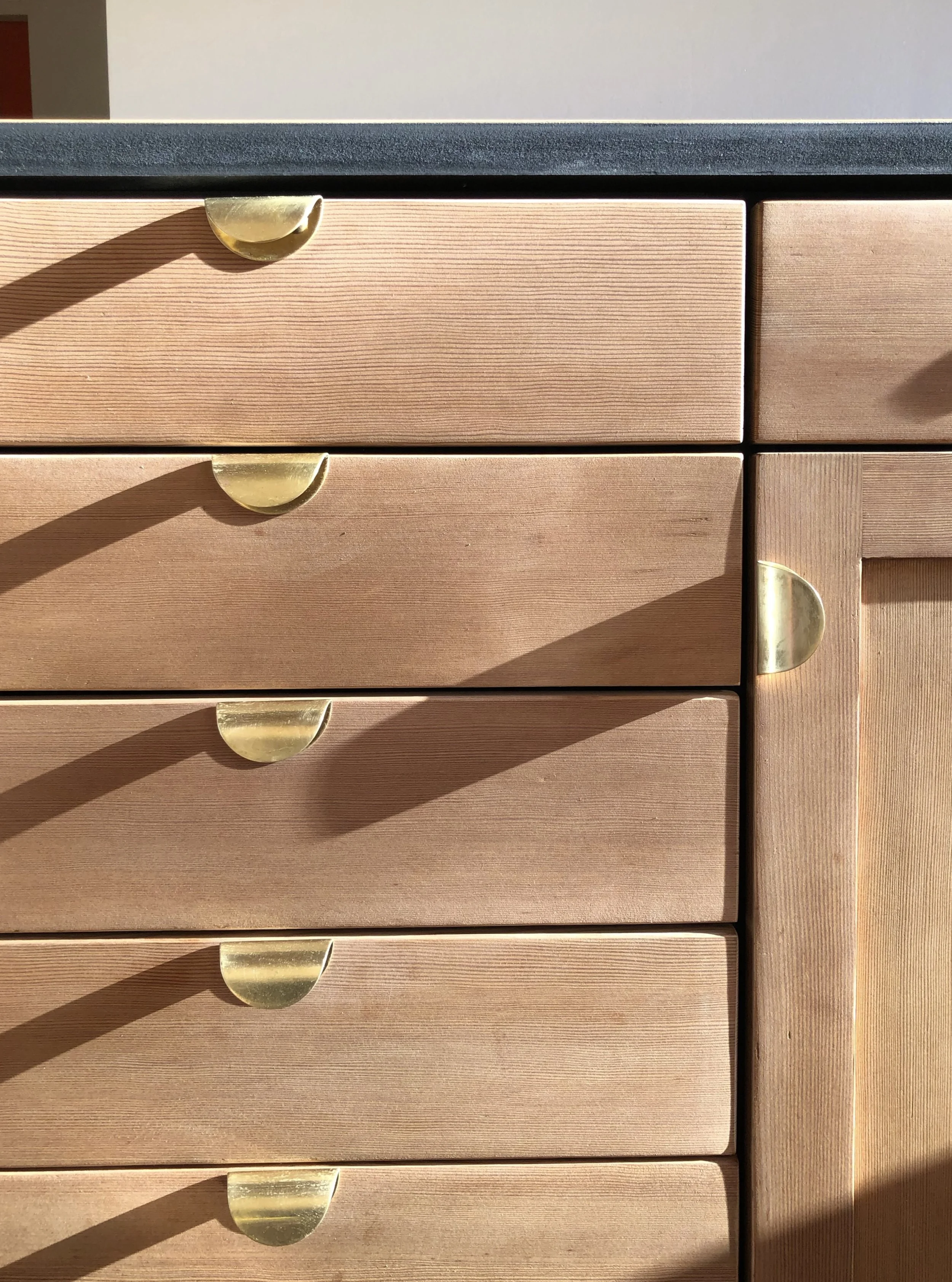 Wooden cabinet drawers with brass half-moon handles.