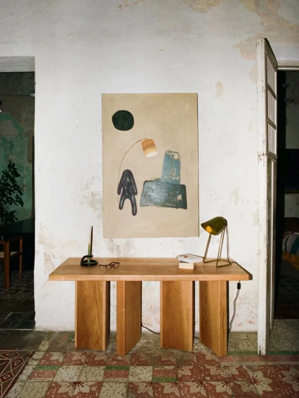 Interior with a wooden table, a lamp, and art on wall