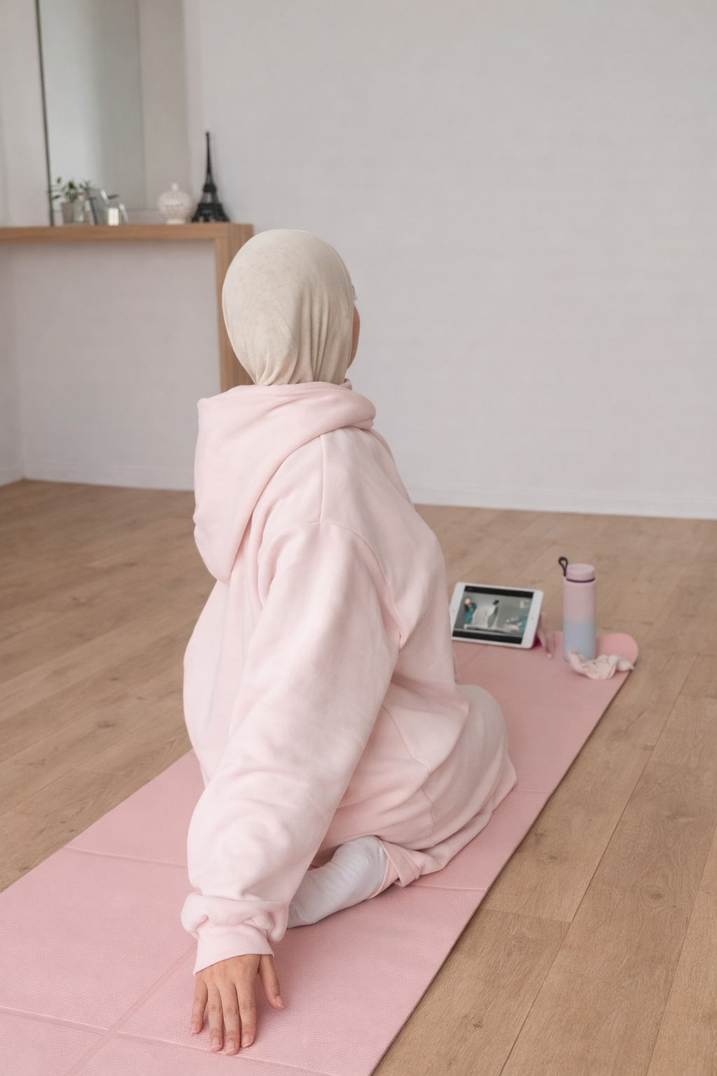 Muslim woman on a pink exercise mat stretching at home