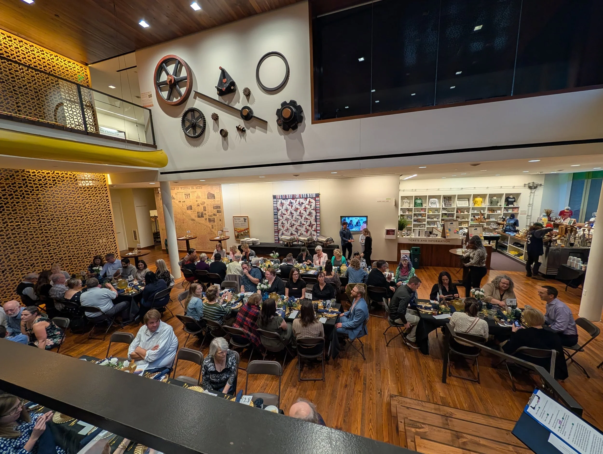 People eat at a fundraiser dinner in a classy industrial space.