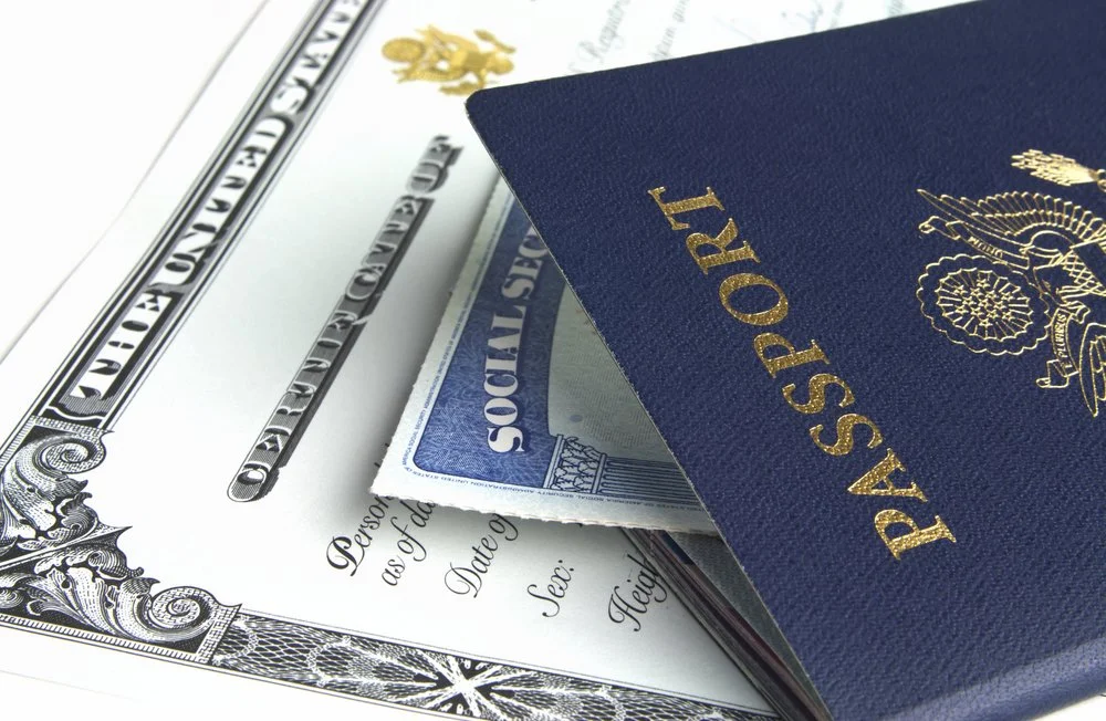 Passport, social security card, and birth certificate fanned out on a table