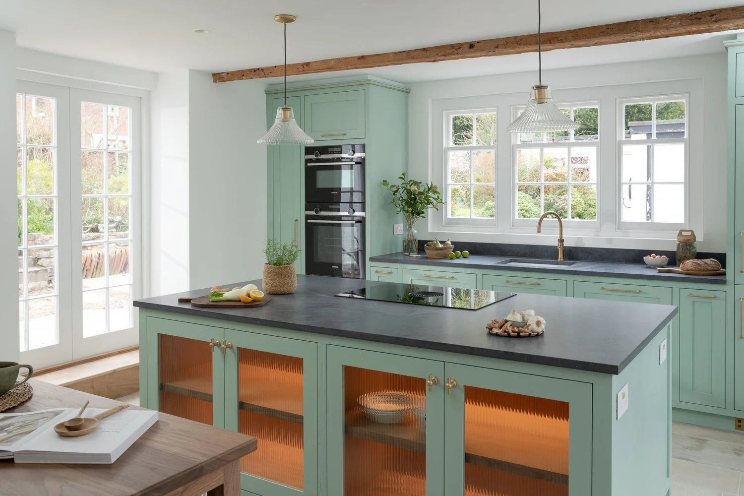 Sage green shaker kitchen with slate topped island and lit walnut cabinets, Topsham, Devon