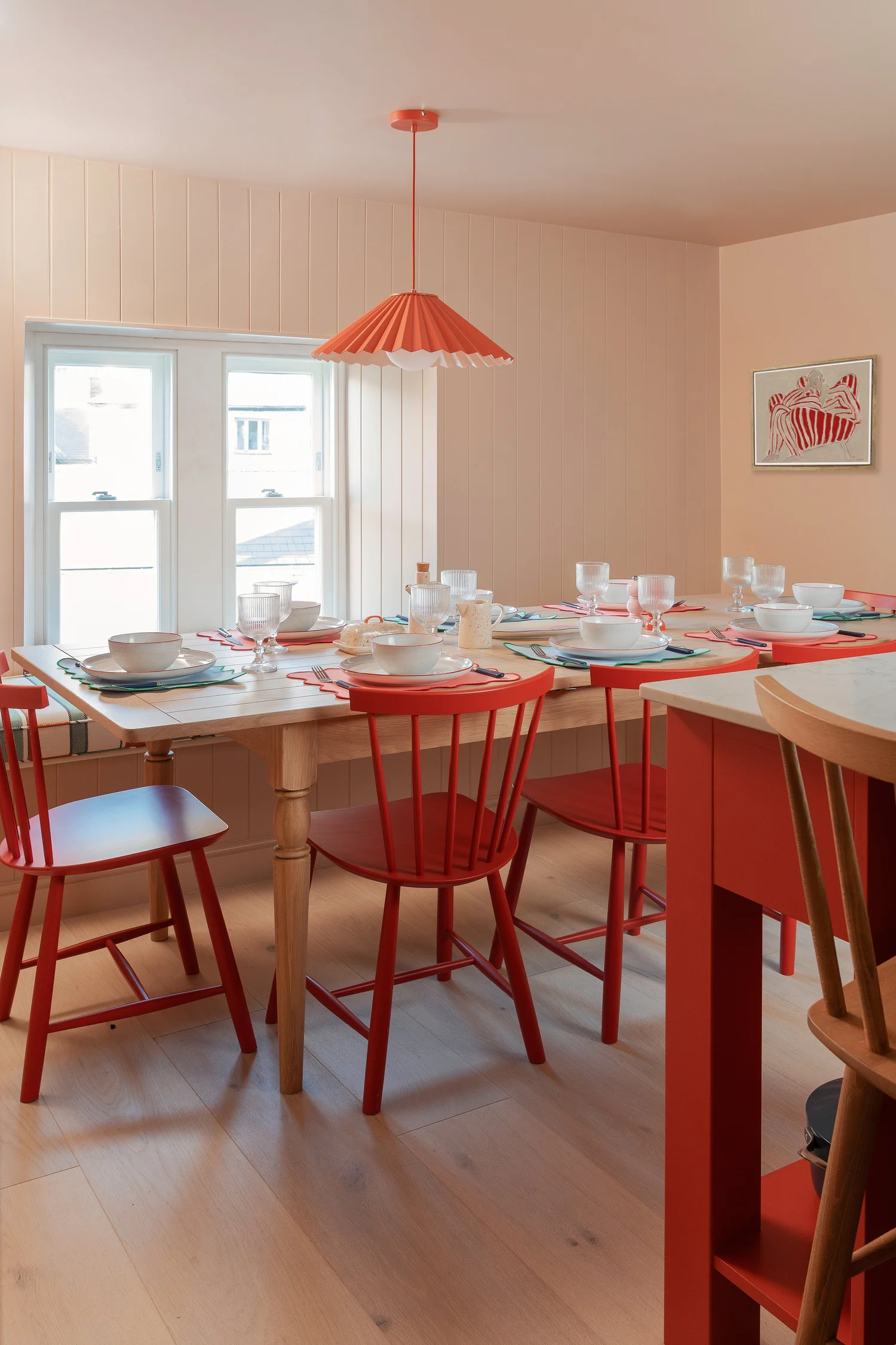 Coral pink dining room with red chairs in St Agnes, Cornwall, by Studio Far West