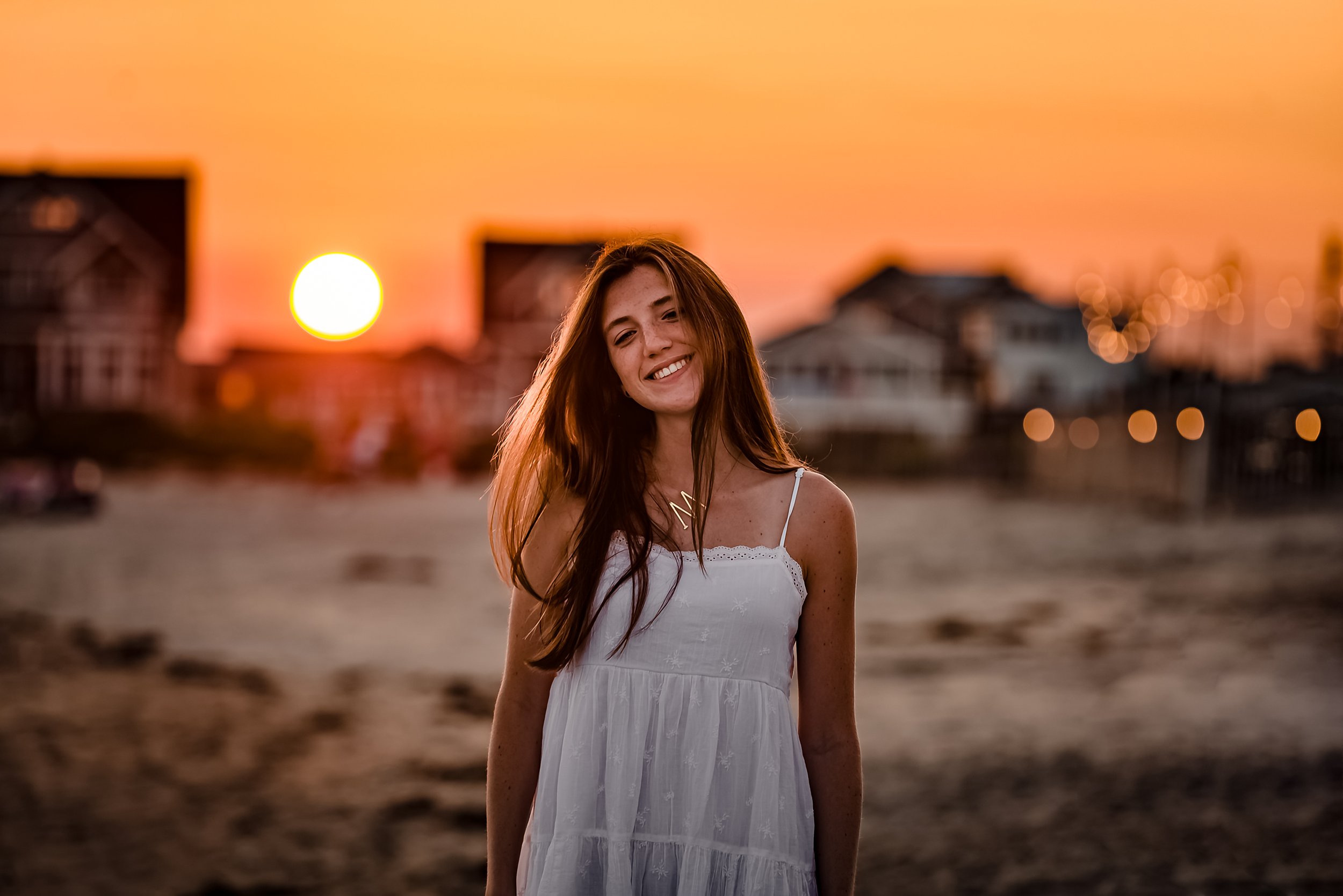 Smiling person in white dress on beach during sunset