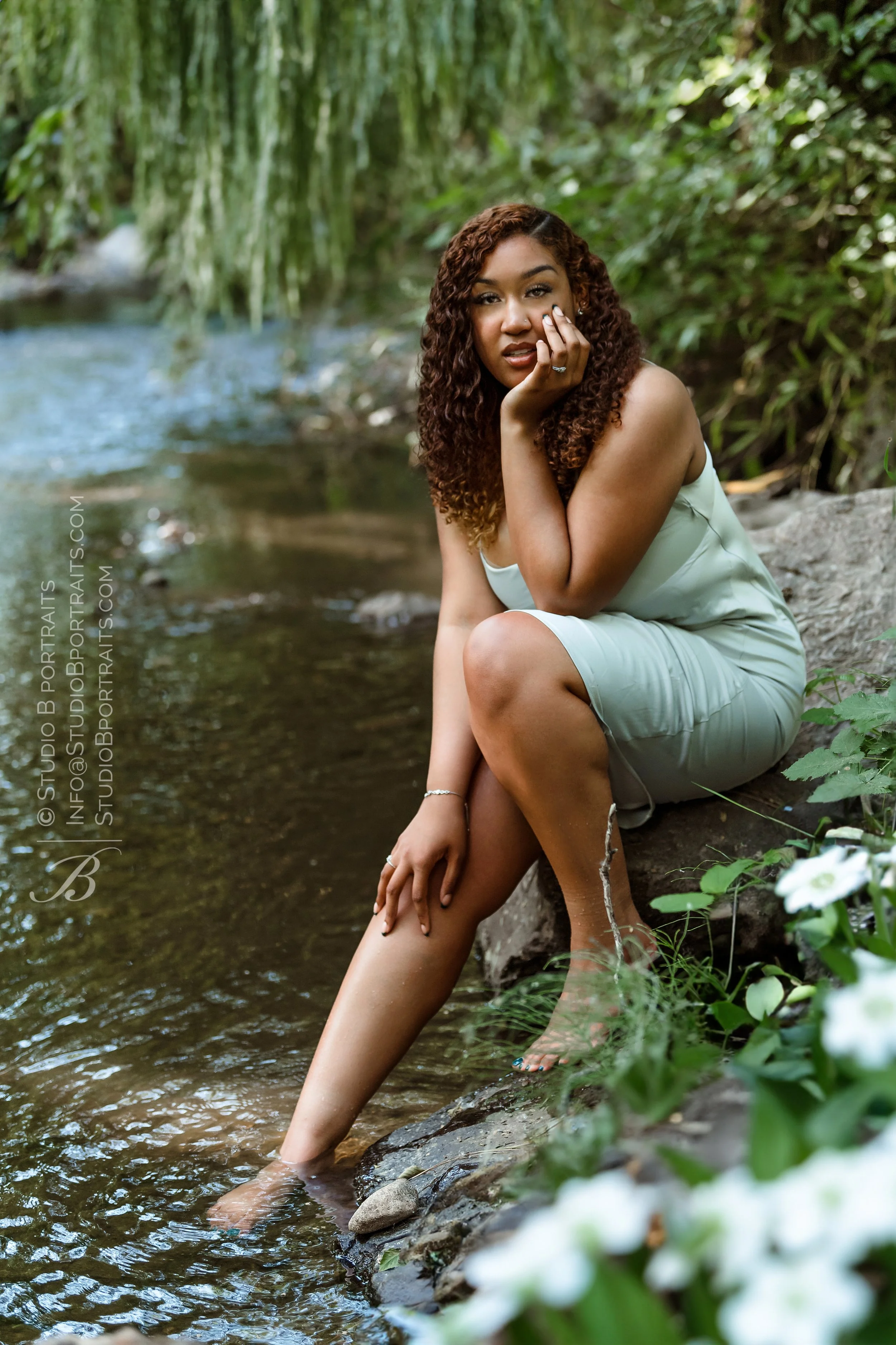 African American girl outdoor senior portraits seated on a rock by Issaquah Creek