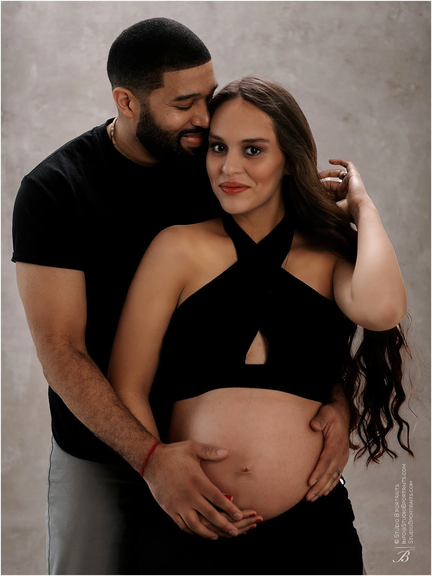 African American and Latina couple in studio posing together for their maternity photo shoot
