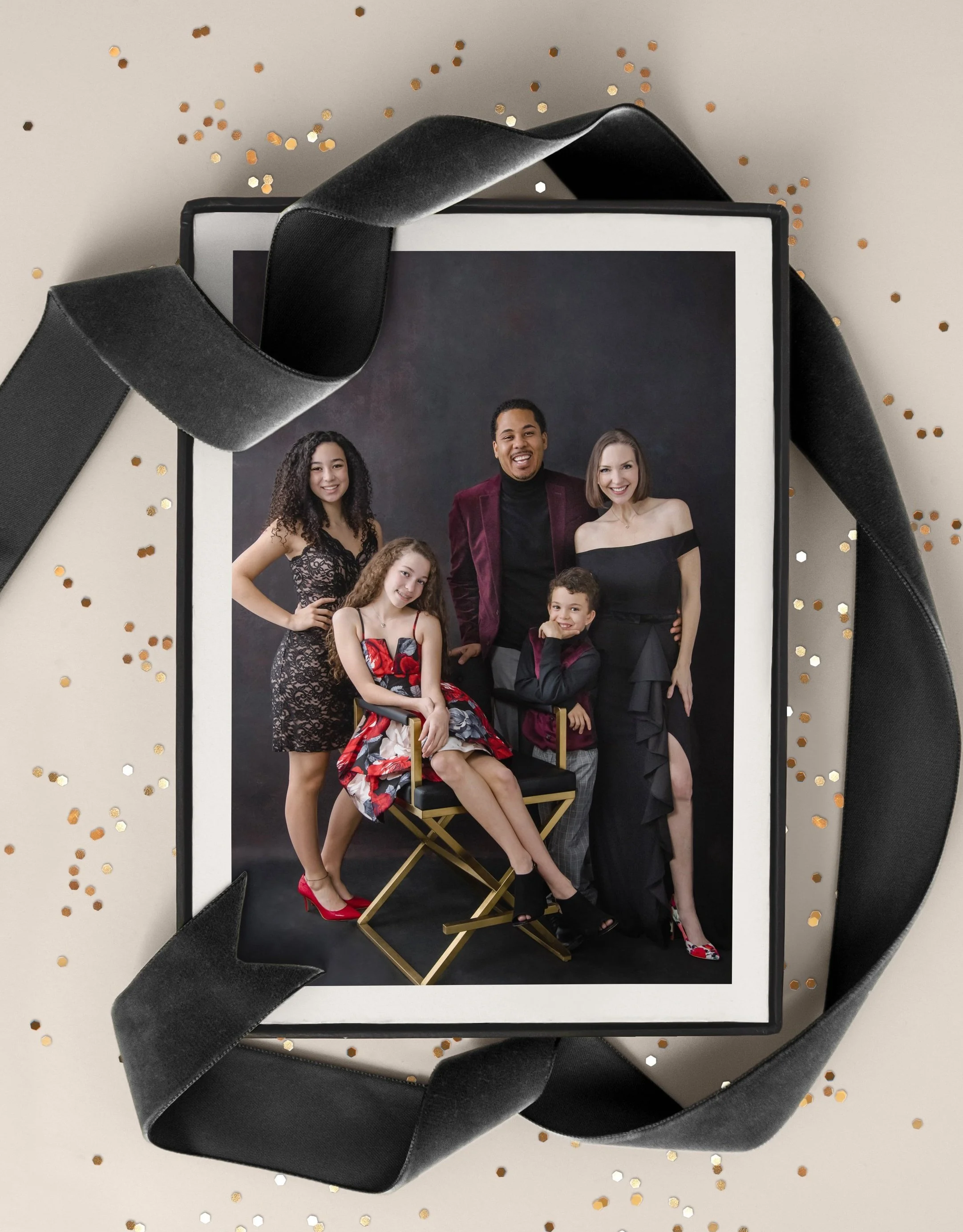A framed photo of a diverse group of five people posing together, surrounded by black ribbon and gold confetti.