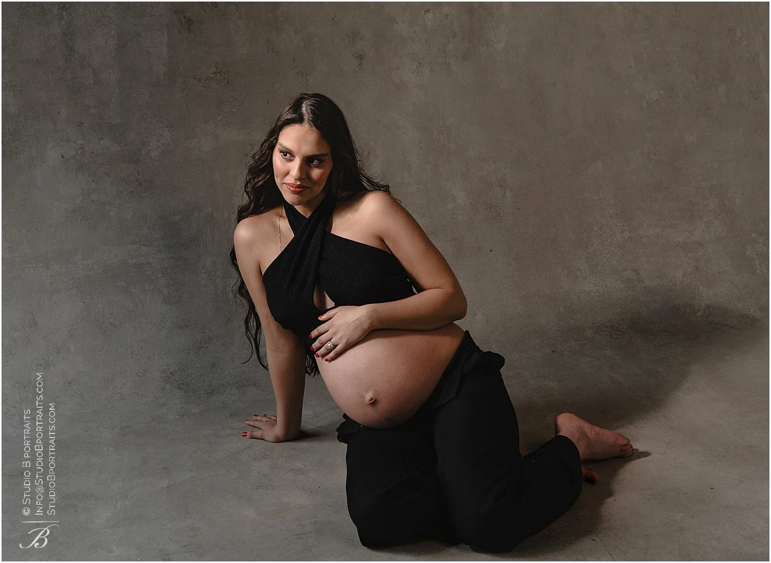 Beautiful Latina posing in studio with her chic outfit showing her pregnant belly