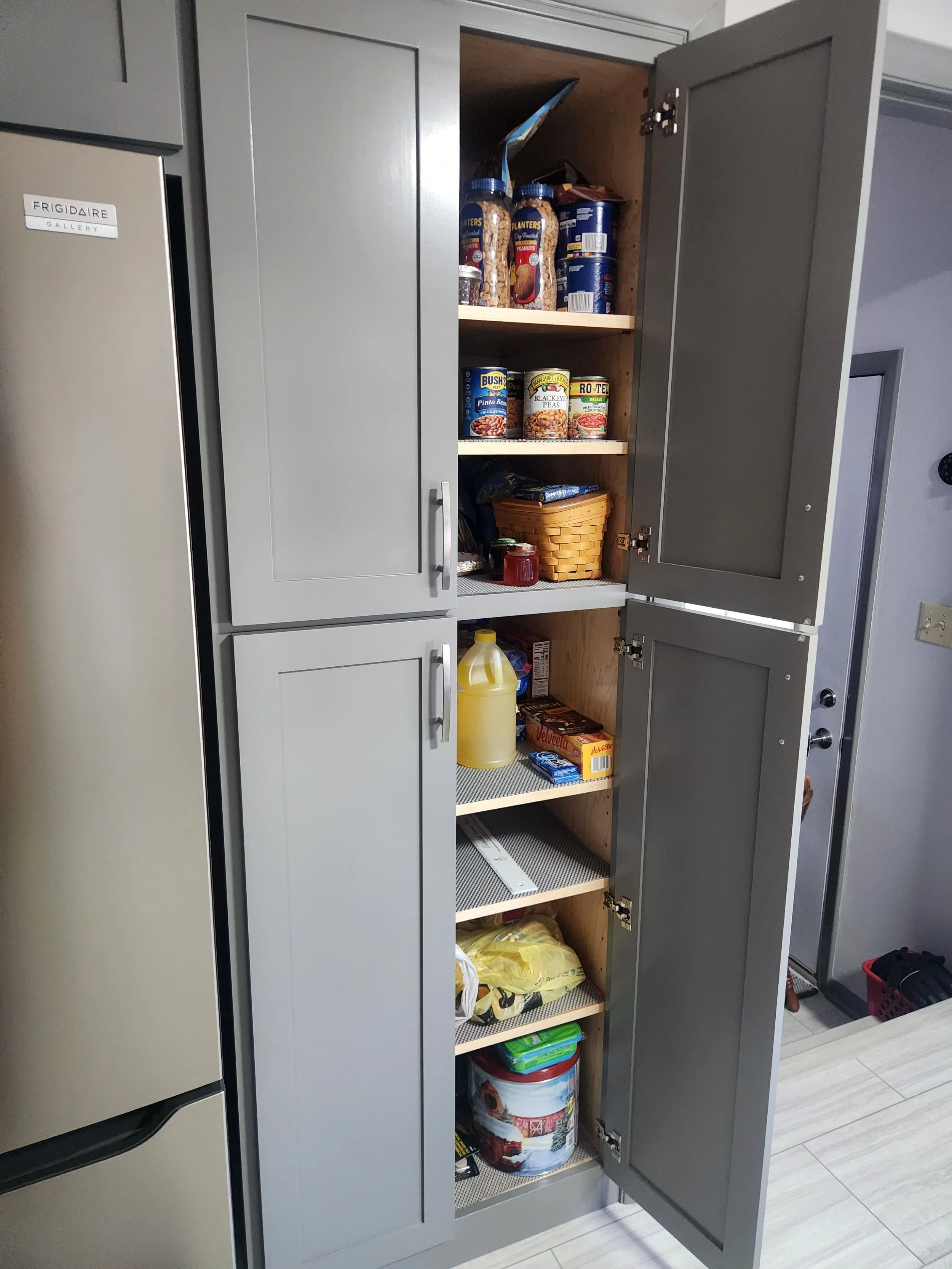 Open kitchen pantry cabinet with various food items and supplies inside.