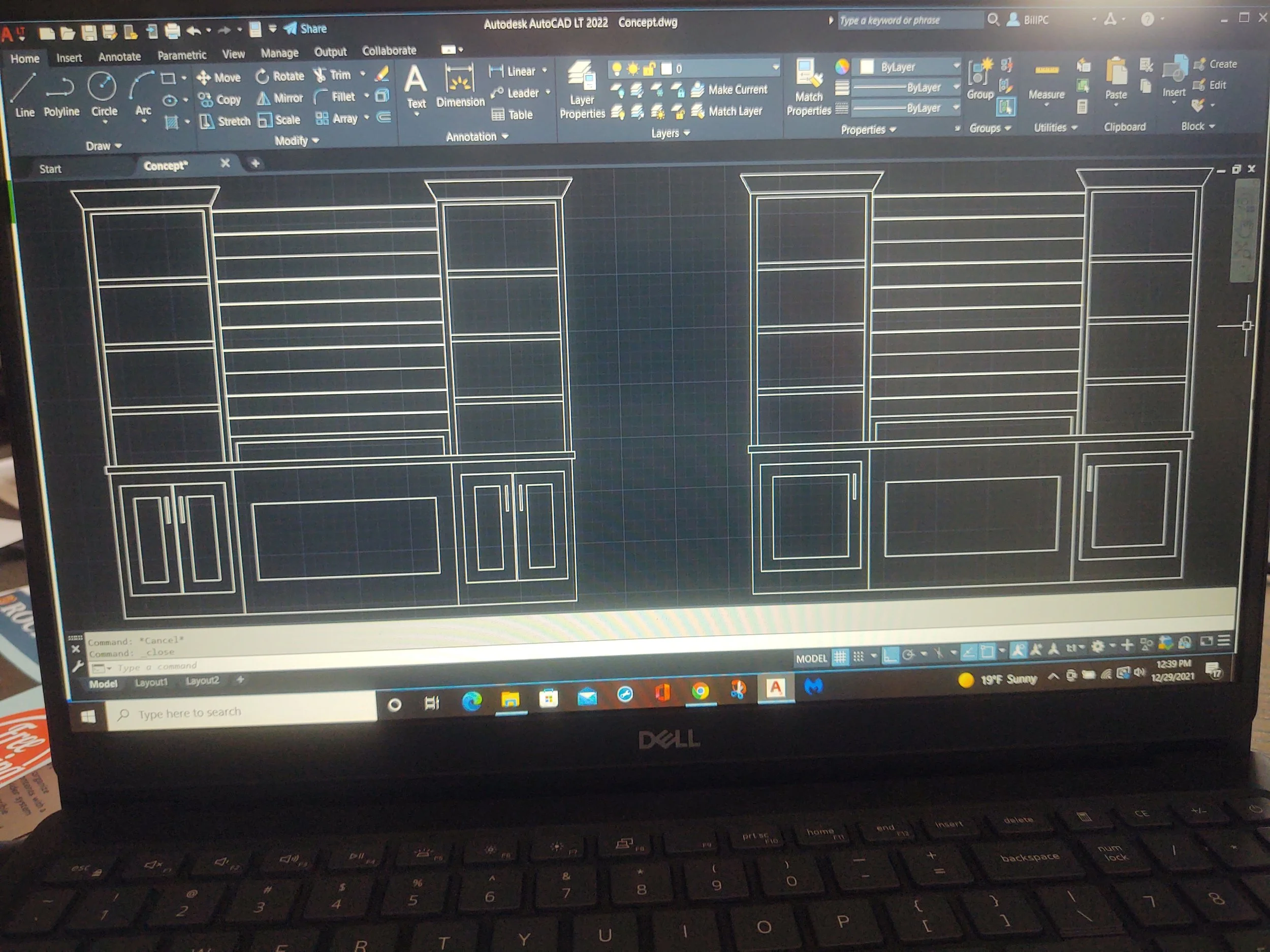 Autodesk AutoCAD LT 2022 software open on a Dell laptop screen displaying a detailed architectural bookshelf design drawing with multiple shelves and cabinet doors.
