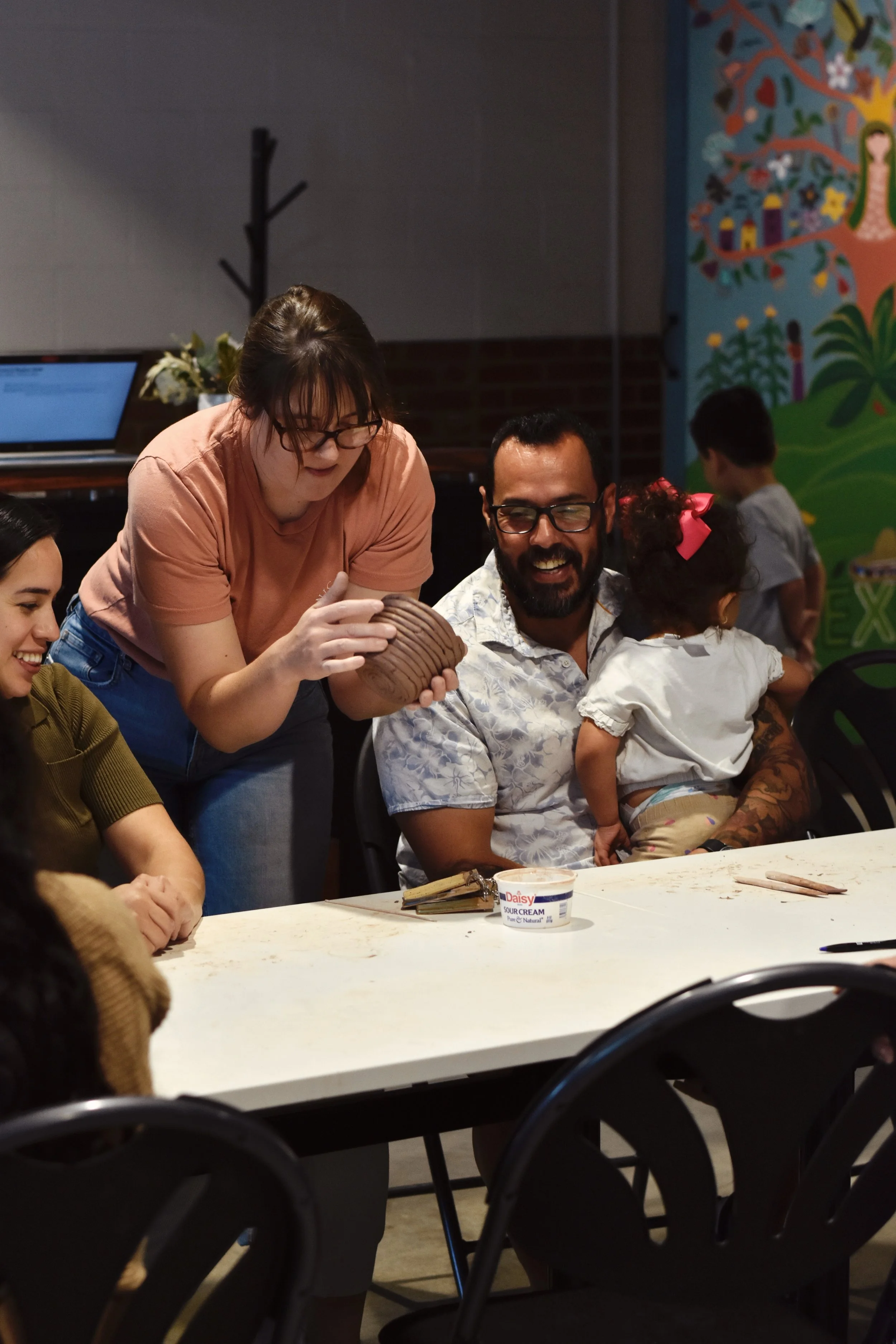 A group of people smile while holding clay