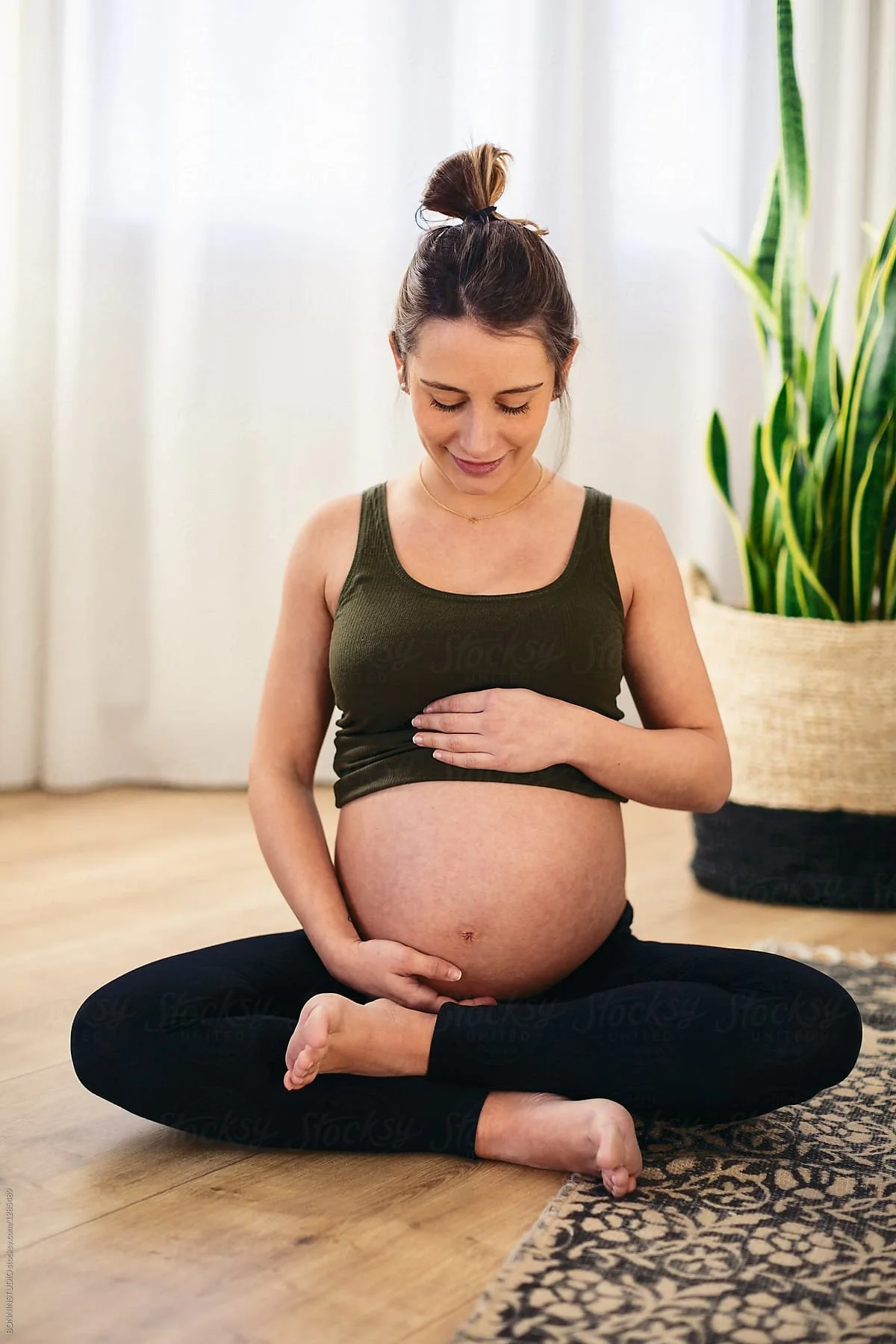 Pregnant woman sitting cross-legged with hands on her bump