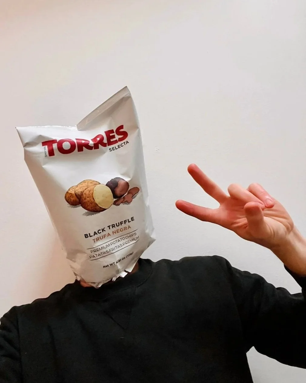 Real Housewives of Clapton, anonymous comedy meme creator's headshot with a bag of Torres black truffle potato chips on his head, making a peace sign with his hand.