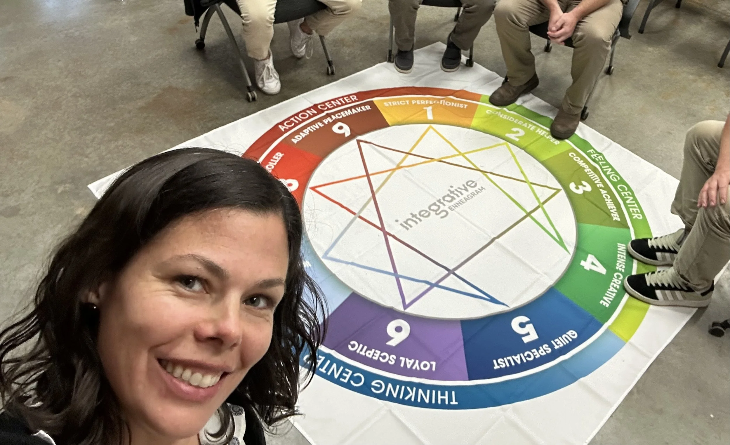 Leadership team gathered around a table during a half-day Enneagram workshop, engaged in open, vulnerable, and curious conversation about team dynamics