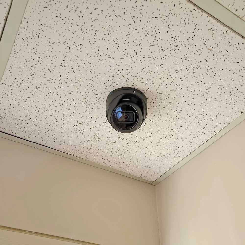 Ceiling camera mounted on a speckled ceiling in an indoor space.