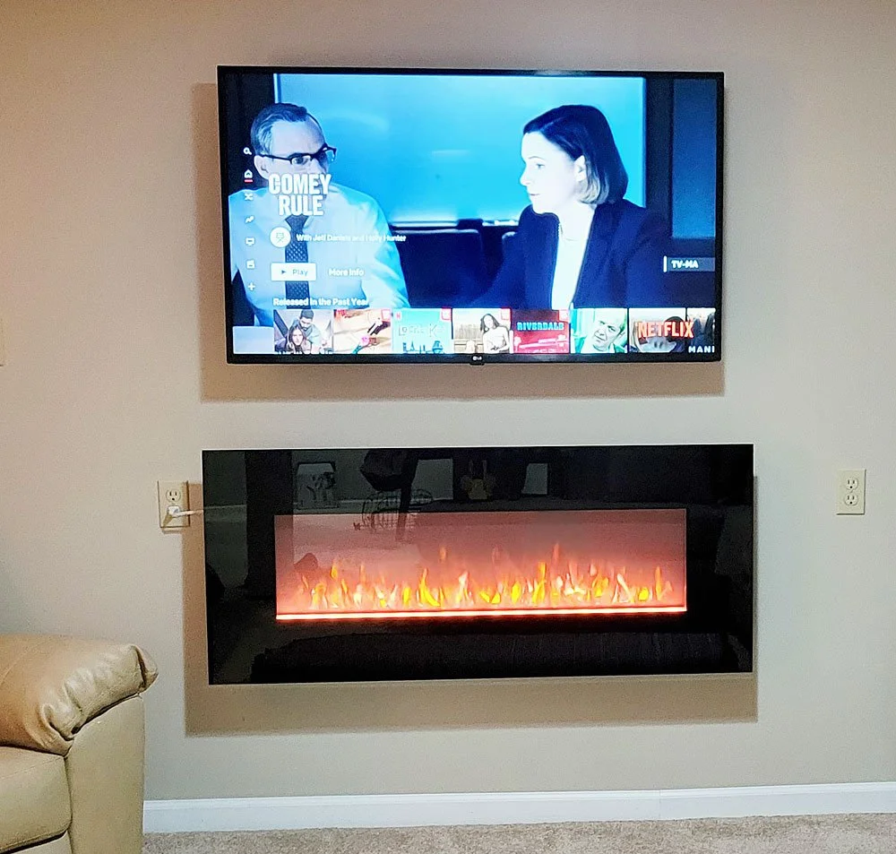 A wall-mounted flat-screen TV displaying a scene from the show 'Comey Rule,' positioned above a modern electric fireplace with orange flames, in a living room setting.